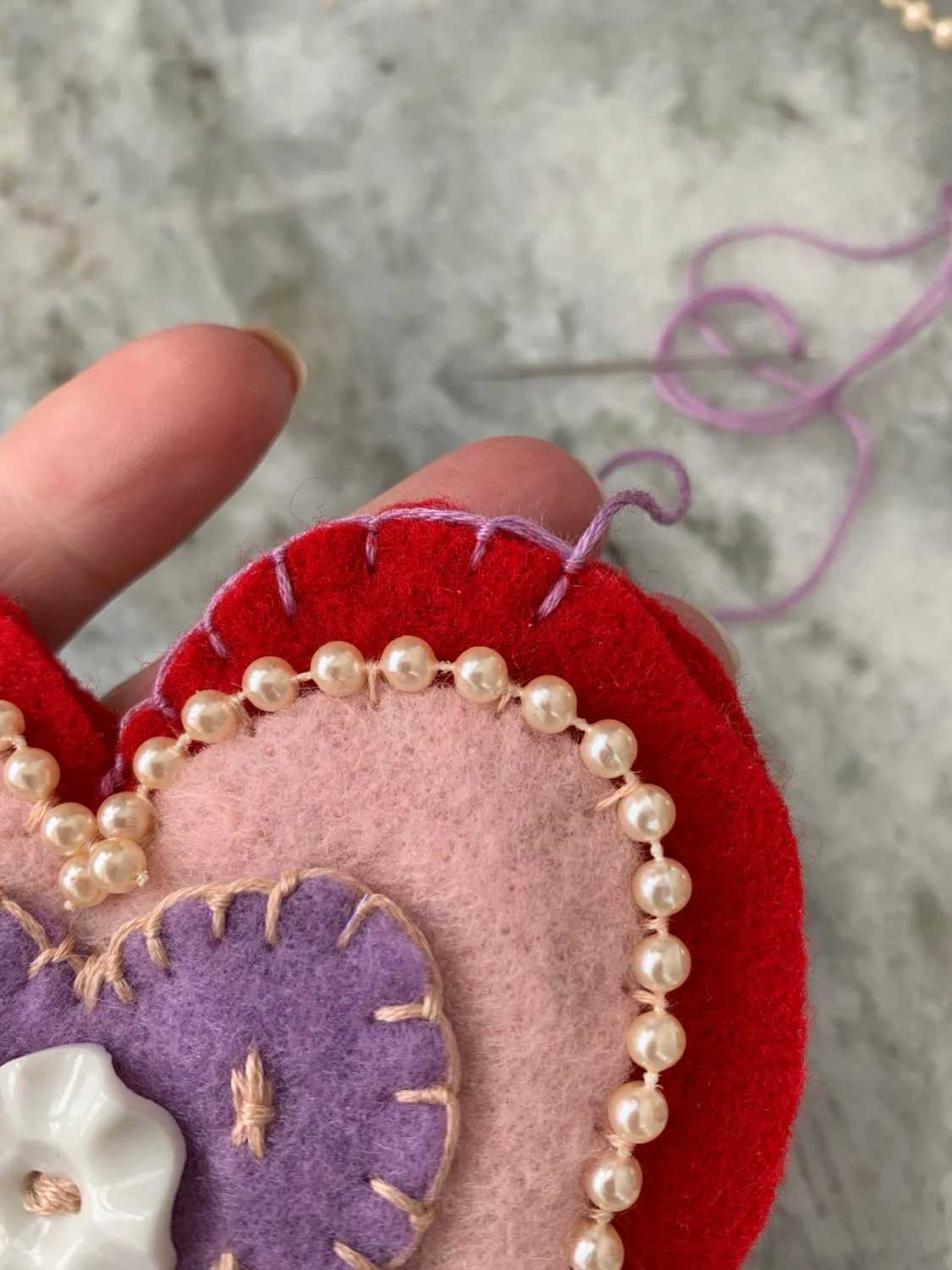 Embroidered layered felt heart shapes with embroidery and bead trim stitched together leaving an opening for filling.