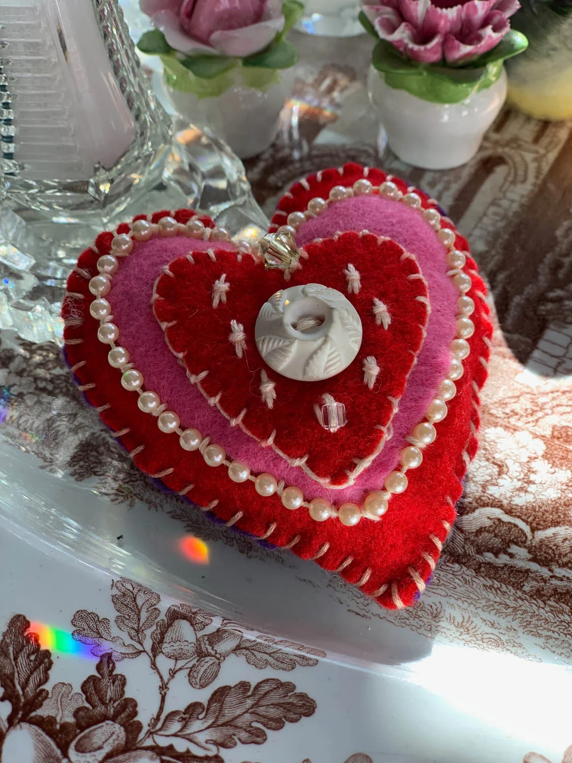 Finished Valentine ornament or pincushion made with embroidery and couched pearl trim on layers of pink and red felt stitched together and stuffed
