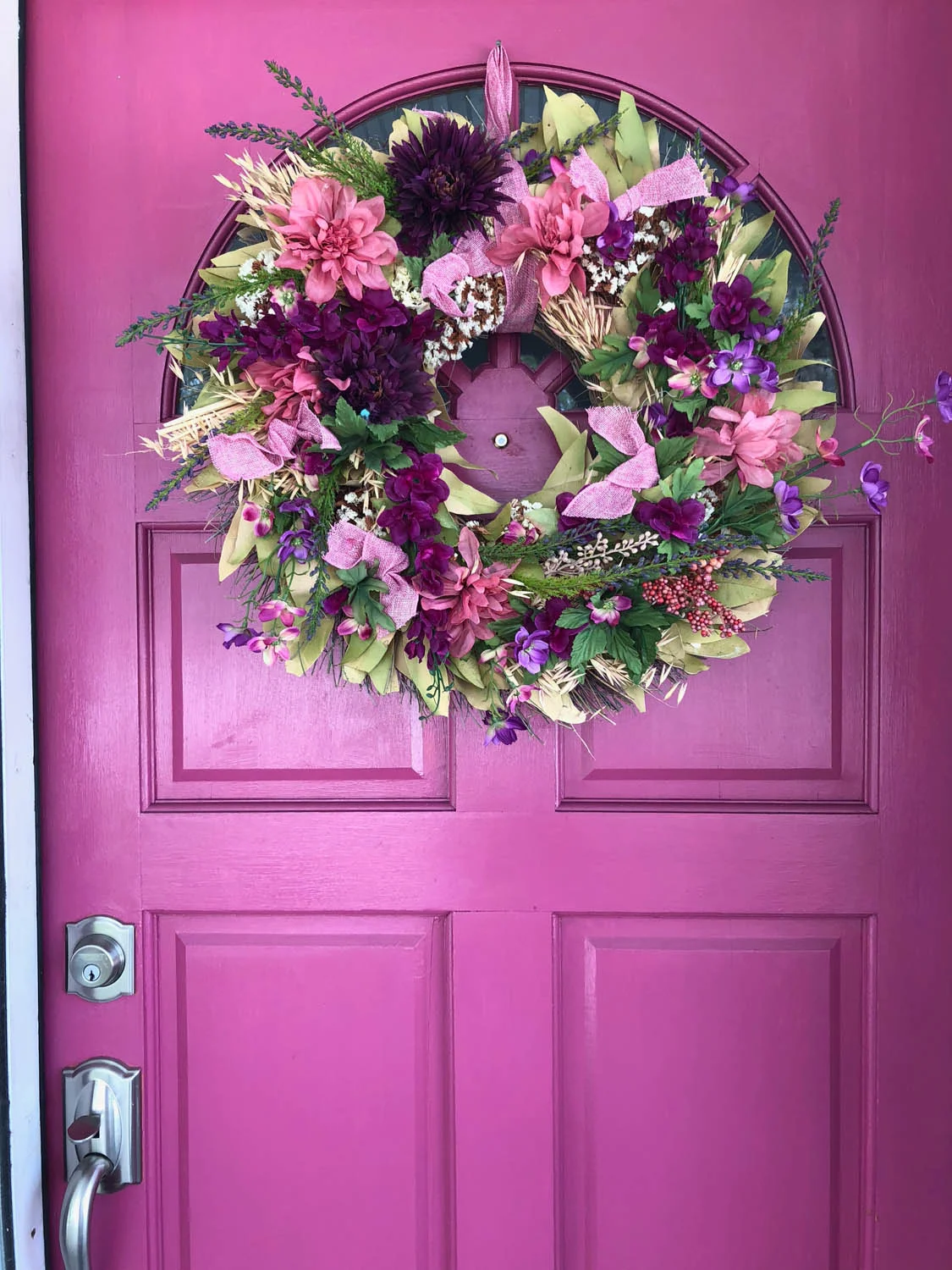 old faded wreath upcycled with fresh silk flowers hung on pink exterior door