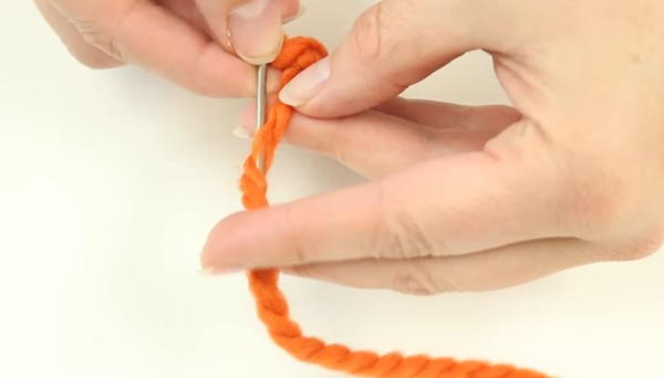 Turning needle and pushing it between plies of yarn