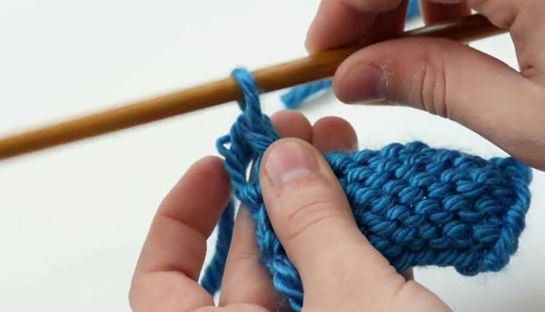 pulling end of yarn through center of final knitted yarn loop