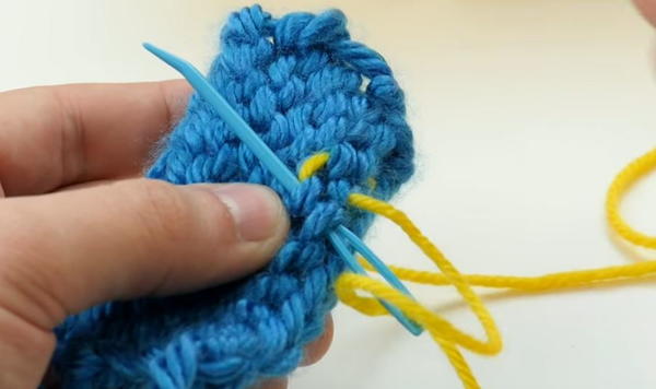 tapestry needle weaving yarn end through back side of knittted swatch