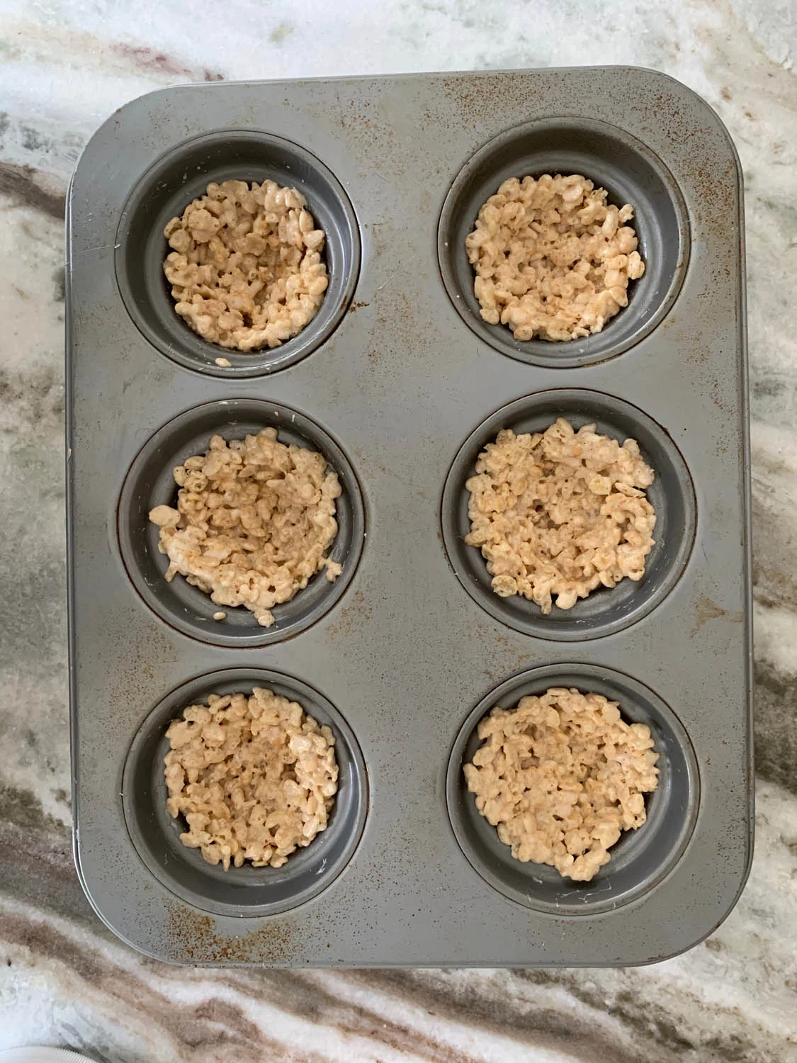 Chilled rice crispy treat recipe shaped into nests in a muffin tin ready to be removed
