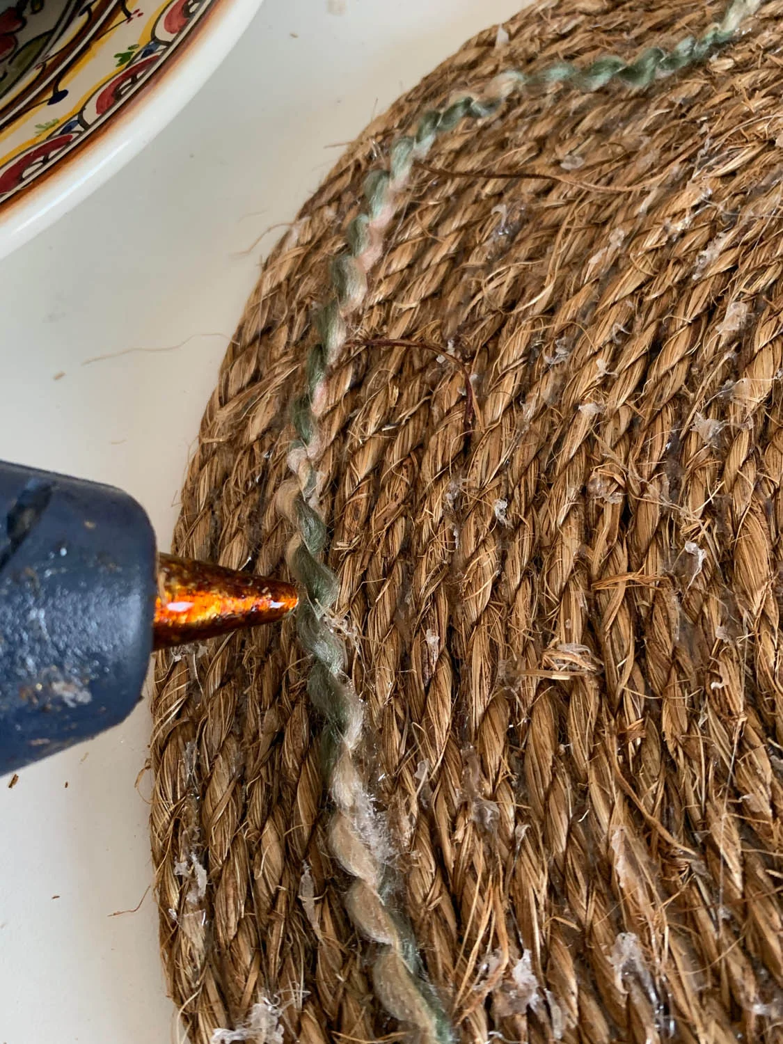 Adding optional yarn or cording to embellish finished DIY rope placemat.