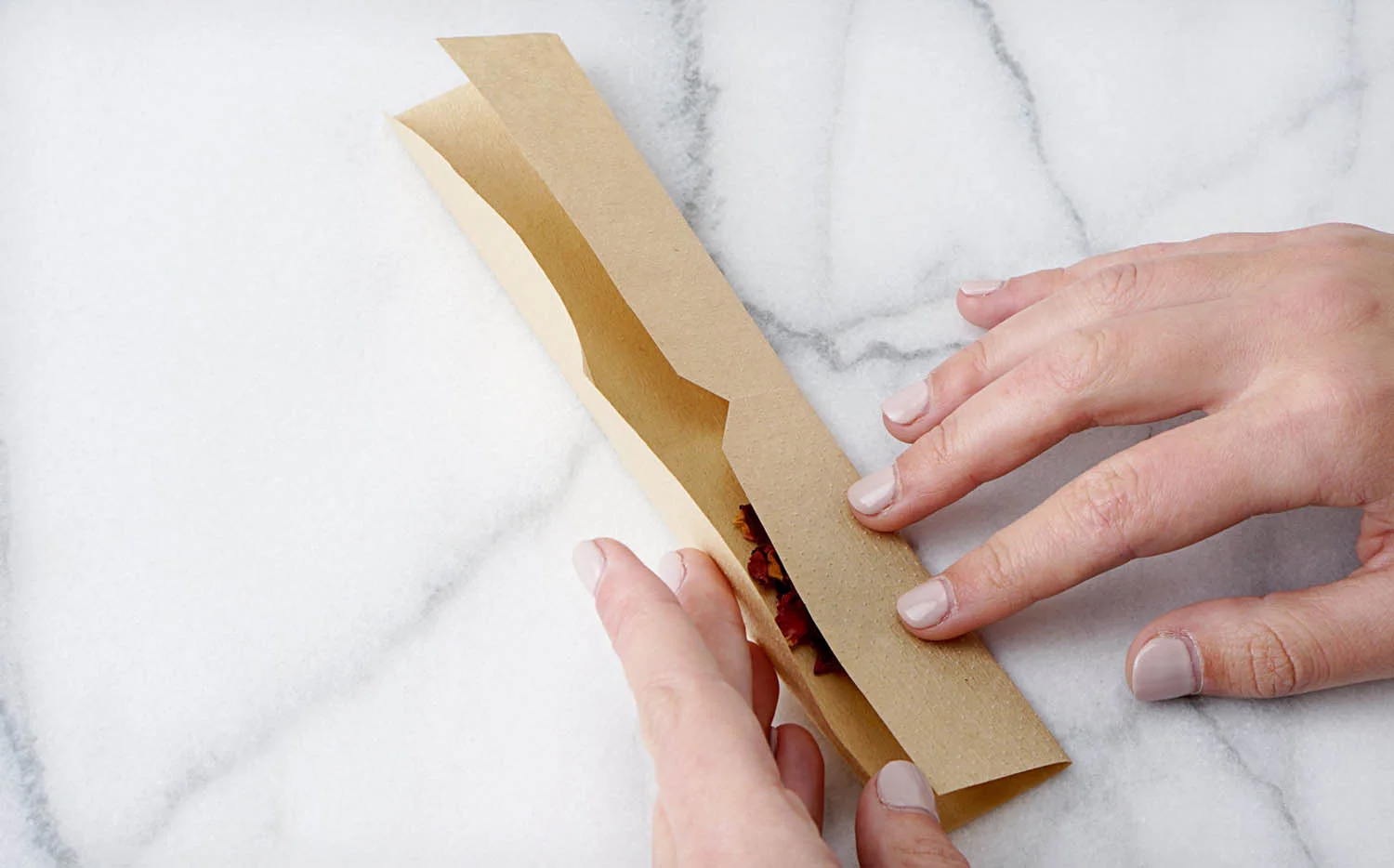 Folding coffee filter paper lengthwise to contain the loose dried tea leaves, herbs, or flower petals