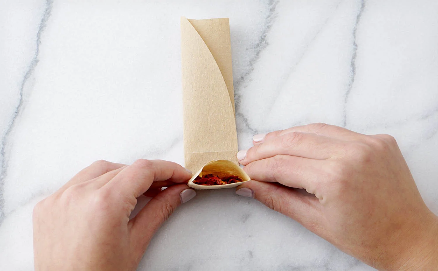 Folding the paper tea filter to contain the loose tea leaves, dried petals or herbs
