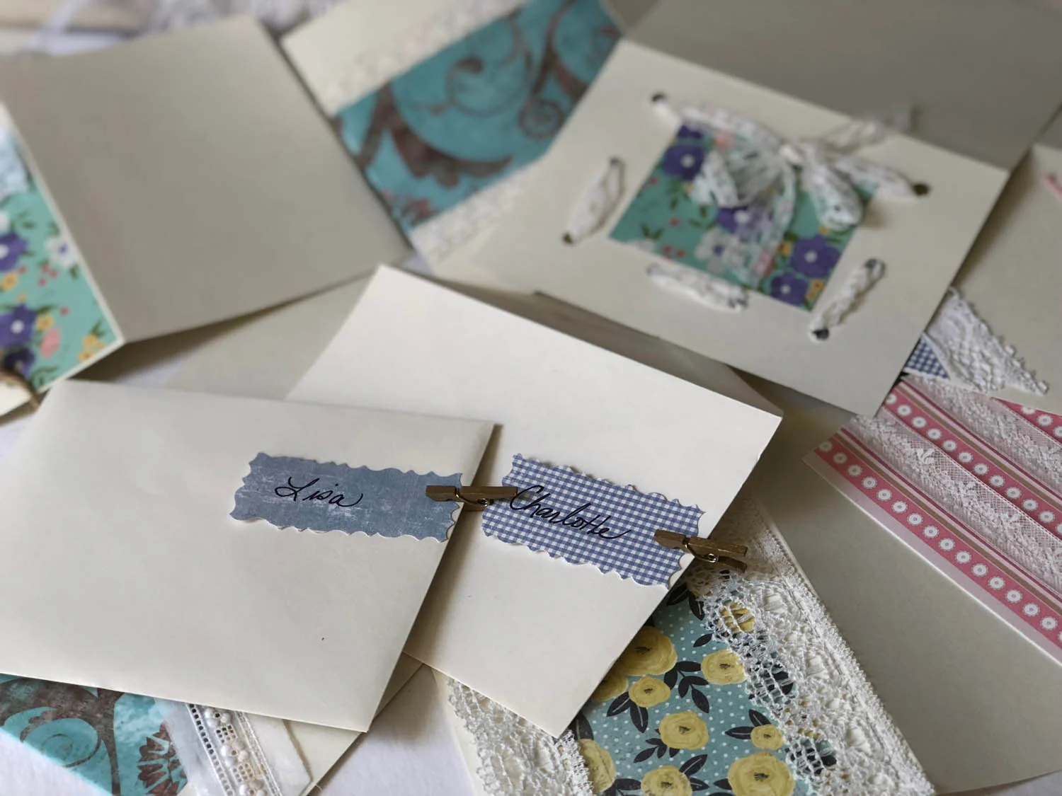 Finished embellished greeting cards with paper craft name tags held to envelopes with mini clothespins