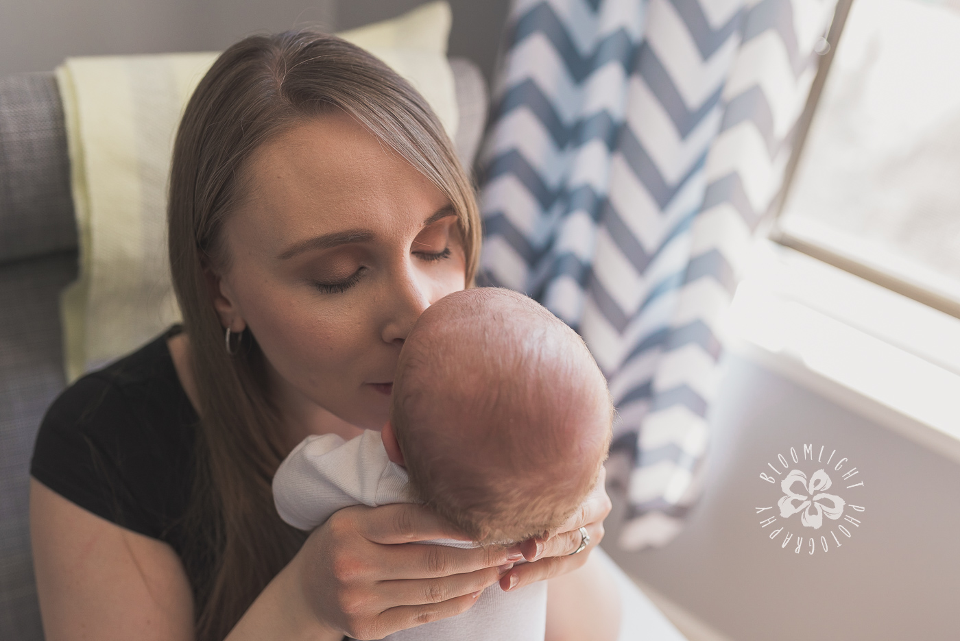 Lovely kiss of a mom on his newborn forehead in their home in Toronto