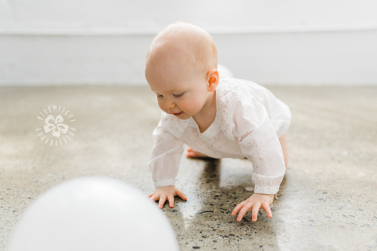 Cute baby wearing white onesie crawling.