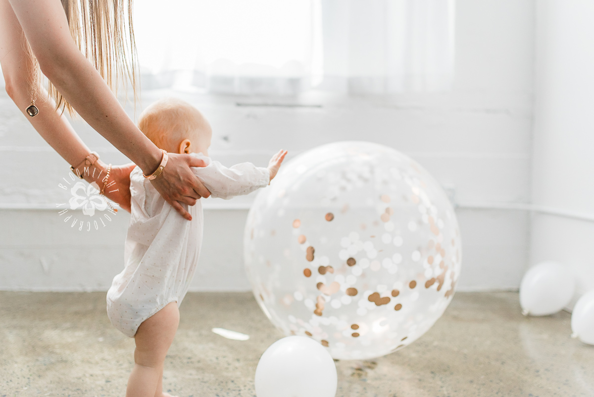 little baby walking with her mom and chasing a big balloon.