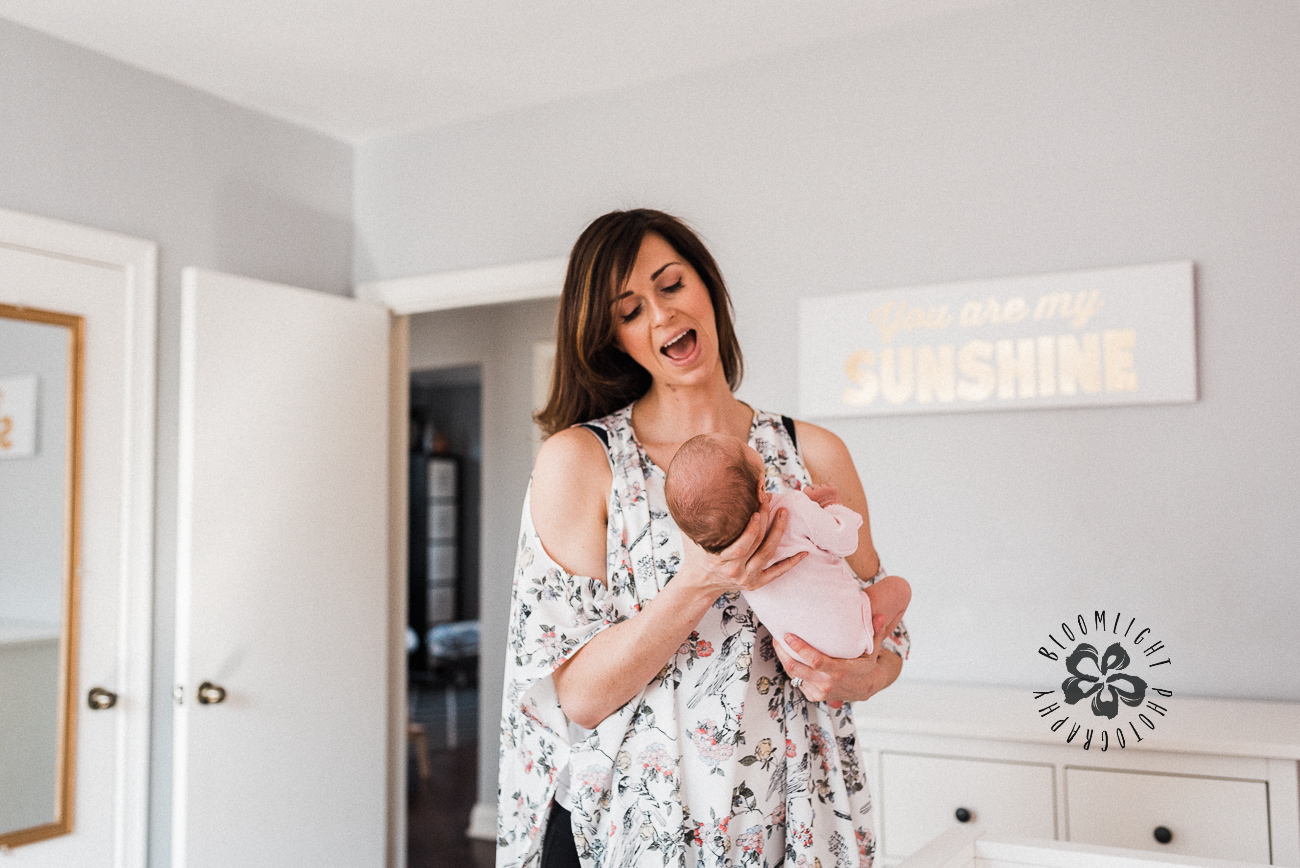 Picture of a happy mom with her newborn in a bright and girly nursery in Toronto