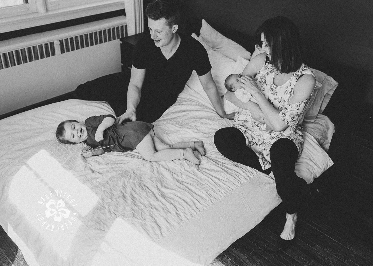 Fun and happy family with a newborn and toddler in their bedroom