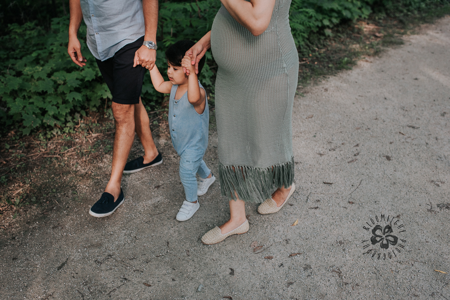 Expecting parents walking in a park with their baby toddler in North York, Toronto