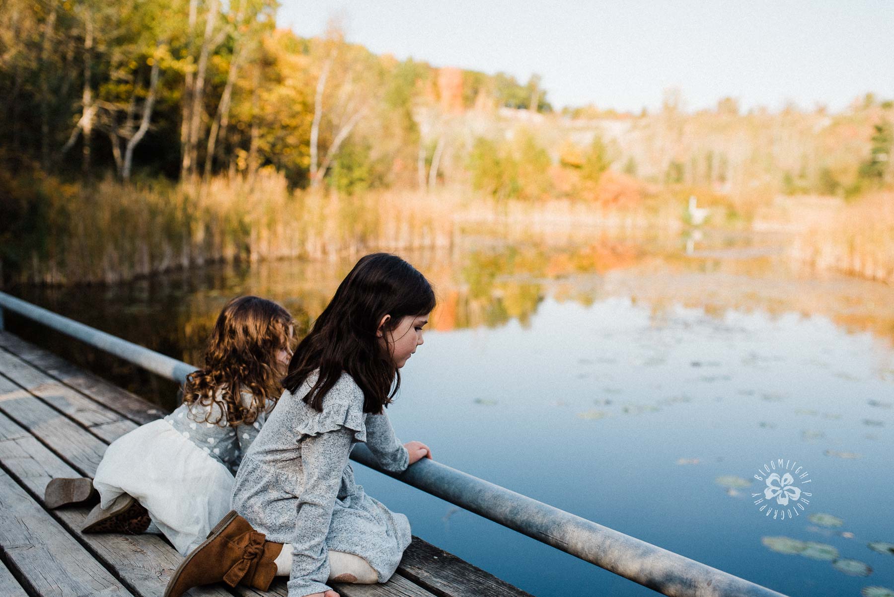 Two children sitting at the deck, looking at water and beautiful nature at Evergreen Brick works 