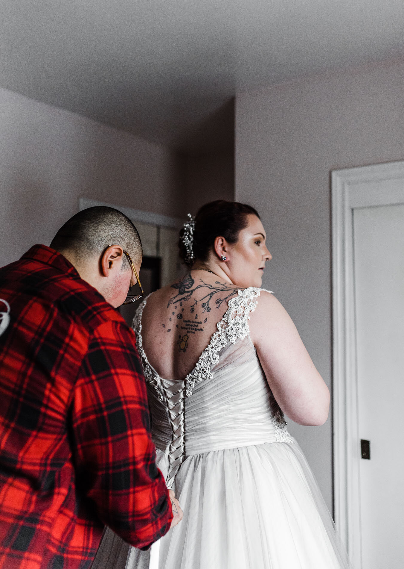 Bride getting ready and wearing dress helped by her bridesmaid