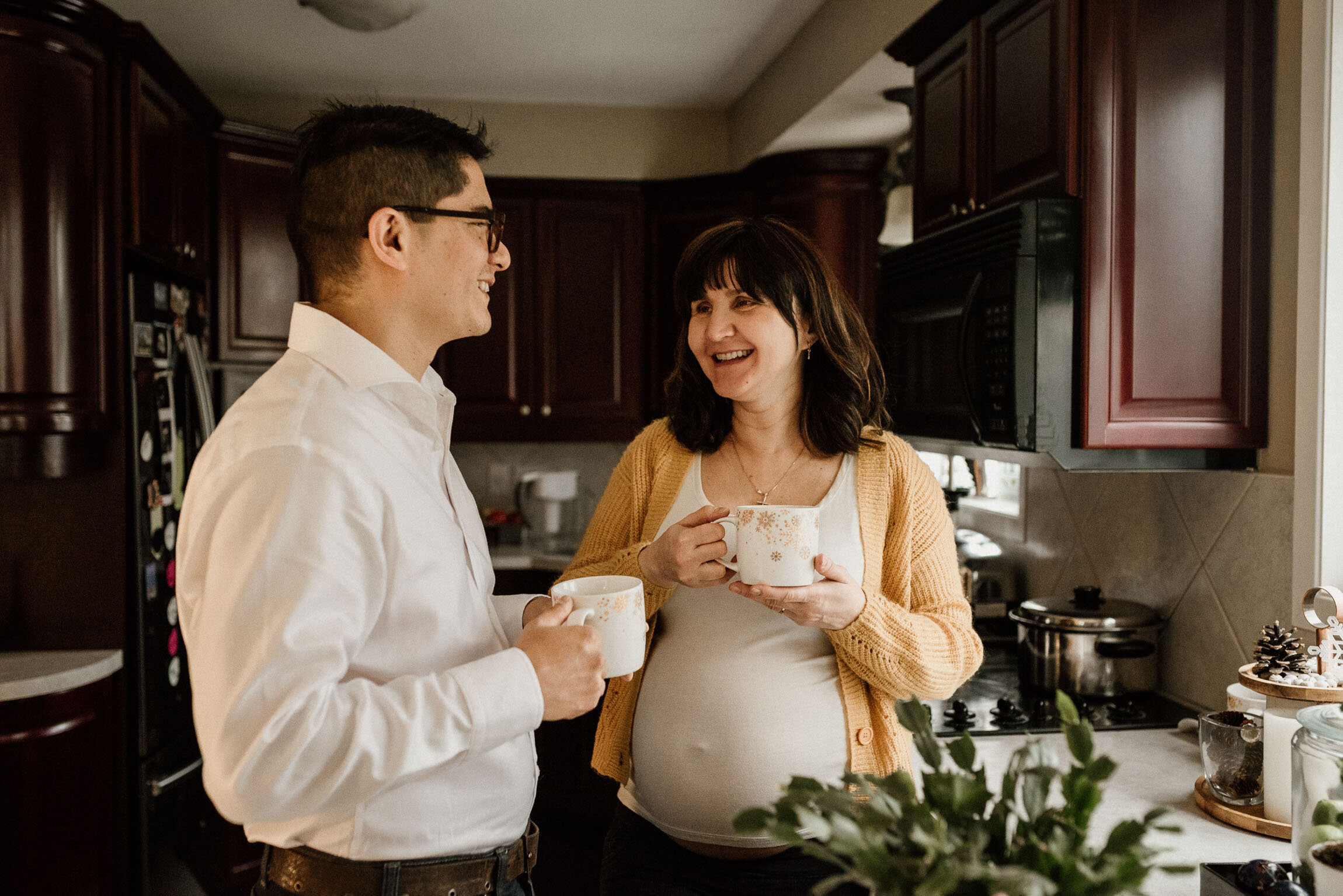 Happy pregnant couple having tea at home