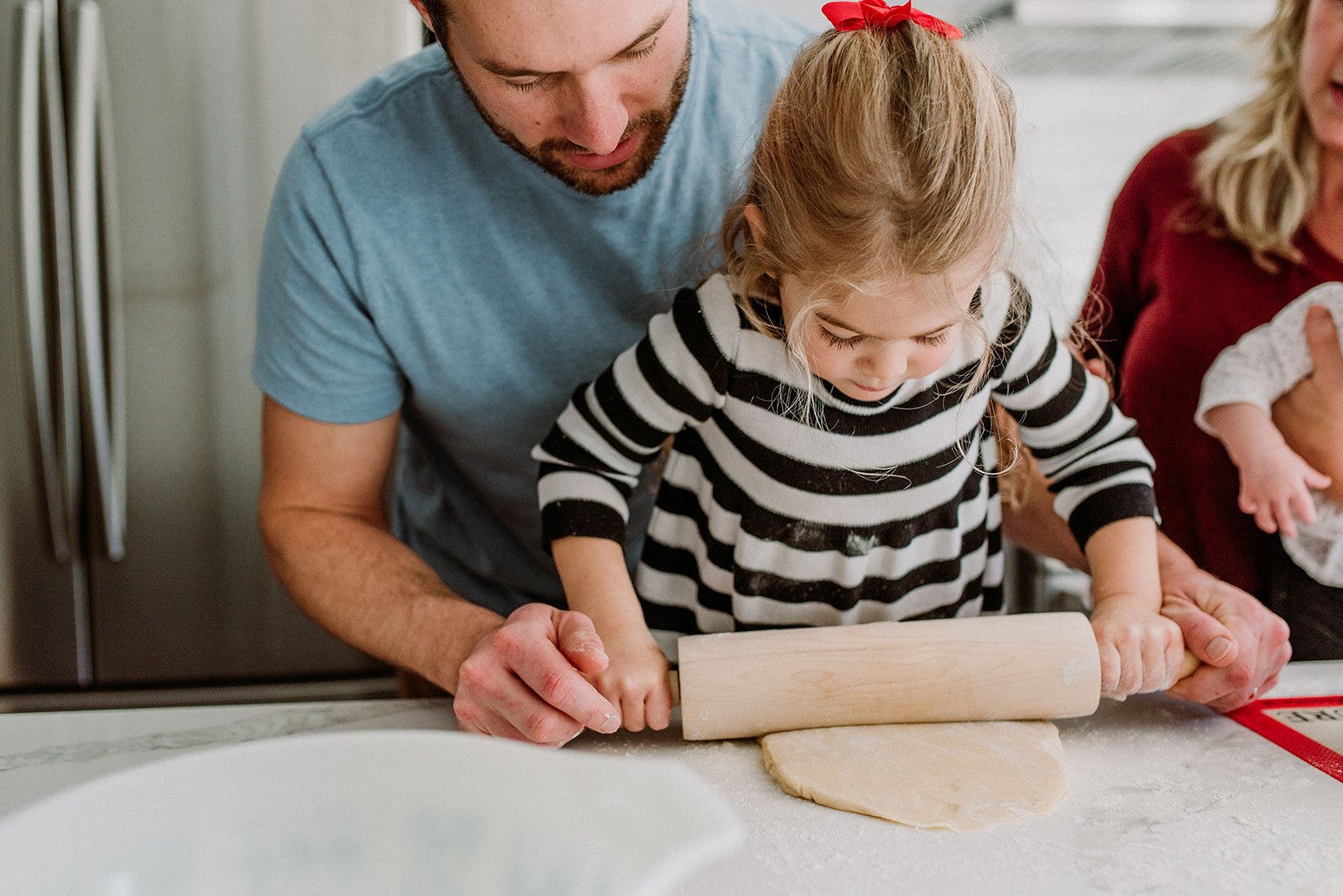 Toddler girl rolling cookie dough with her dad's help