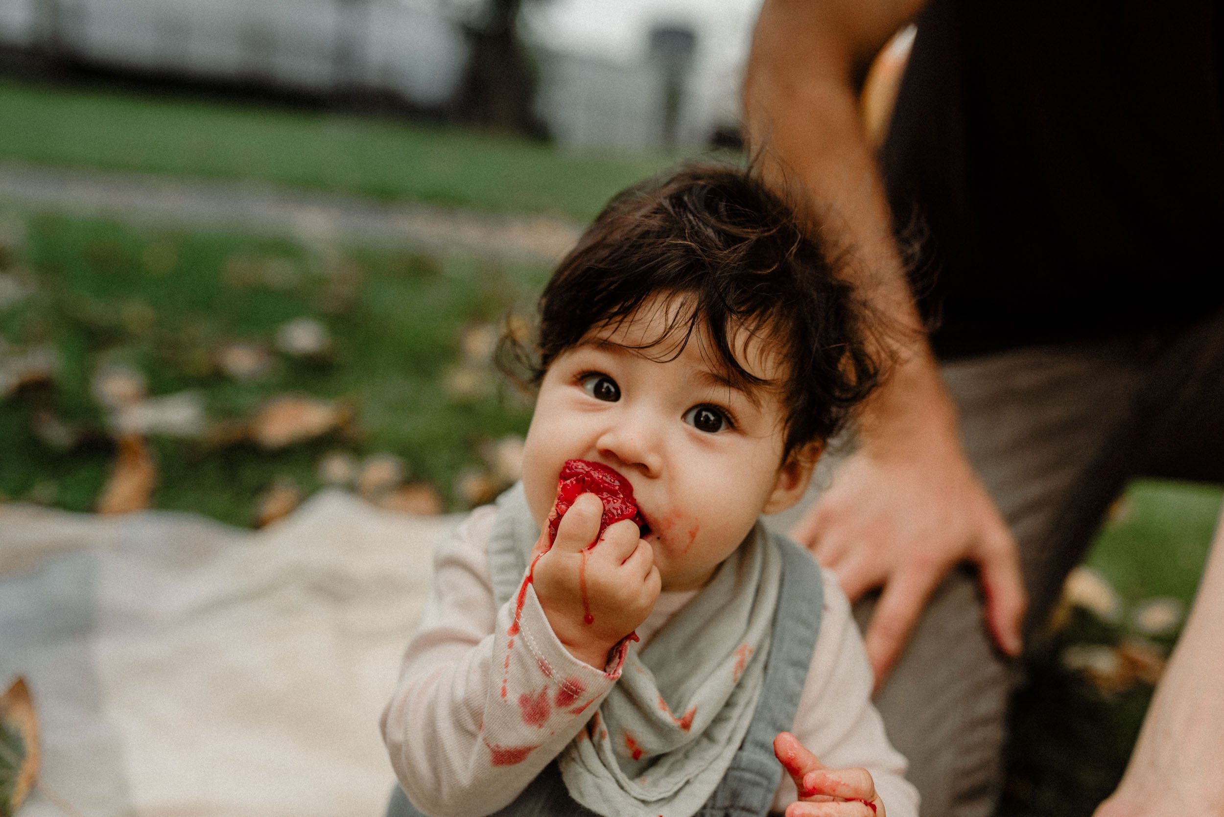 baby eating strawberry while sitting outdoor