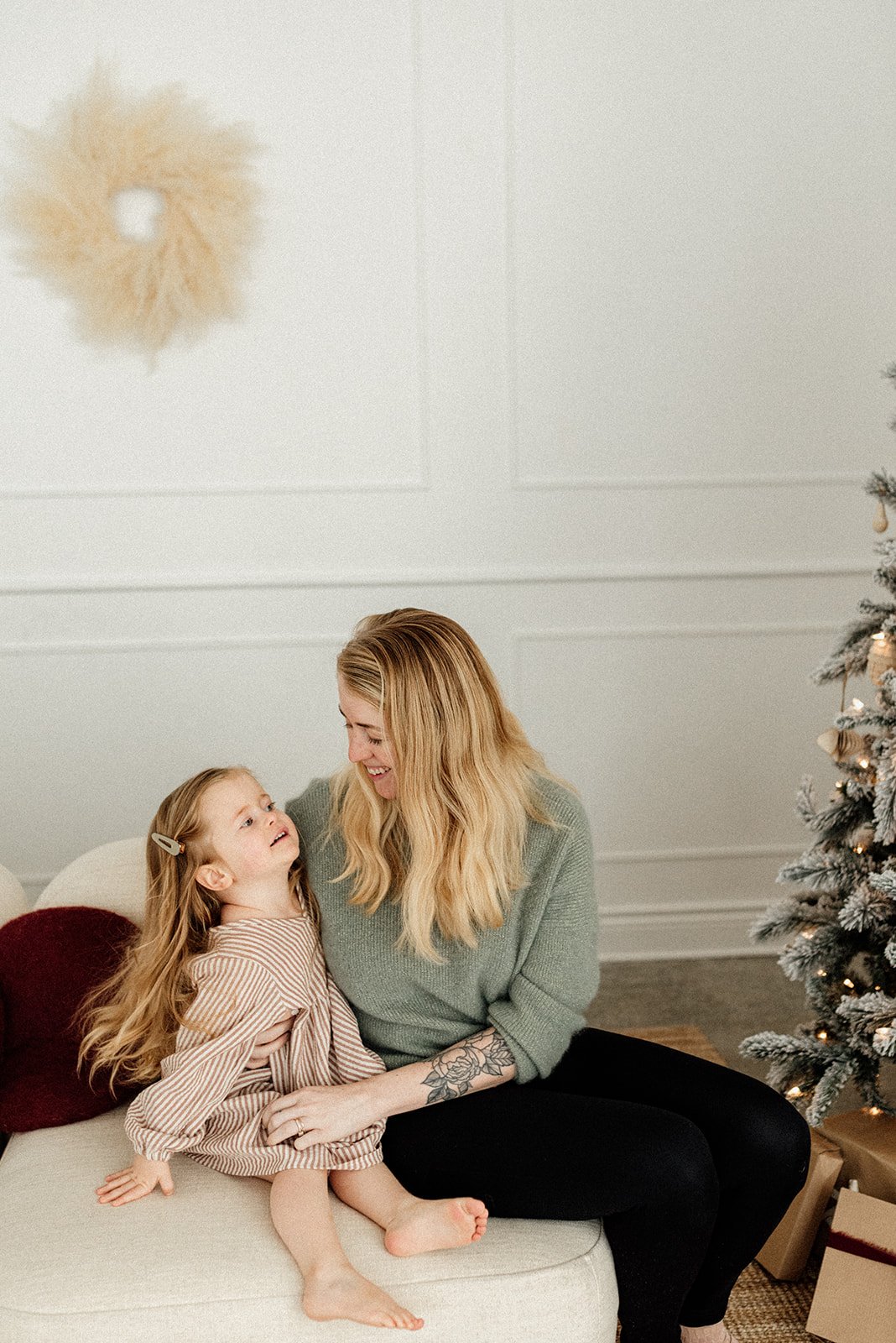 picture of mommy and daughter sitting beside each other happily in Christmas setup