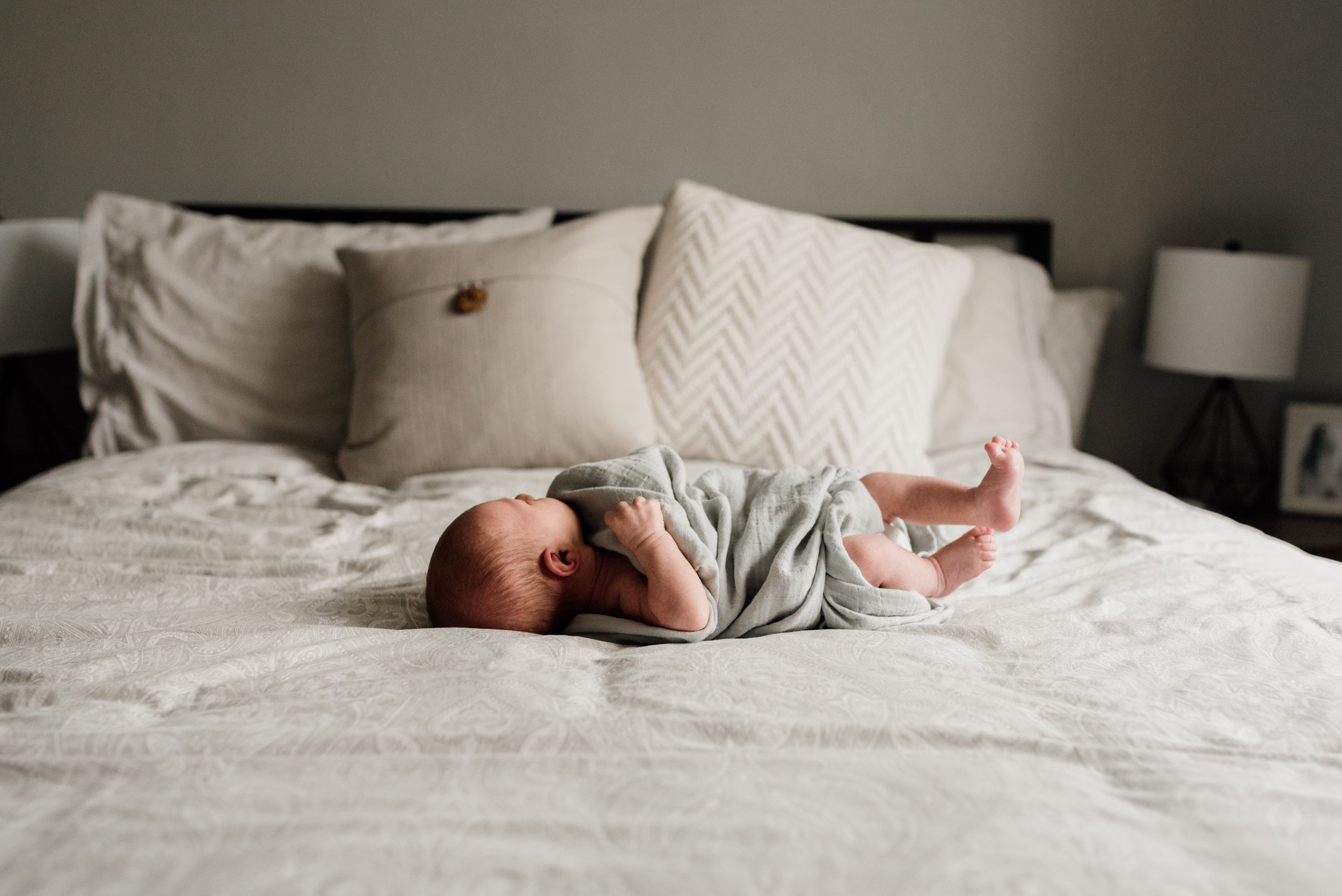 photo of infant wrapped in the bedroom