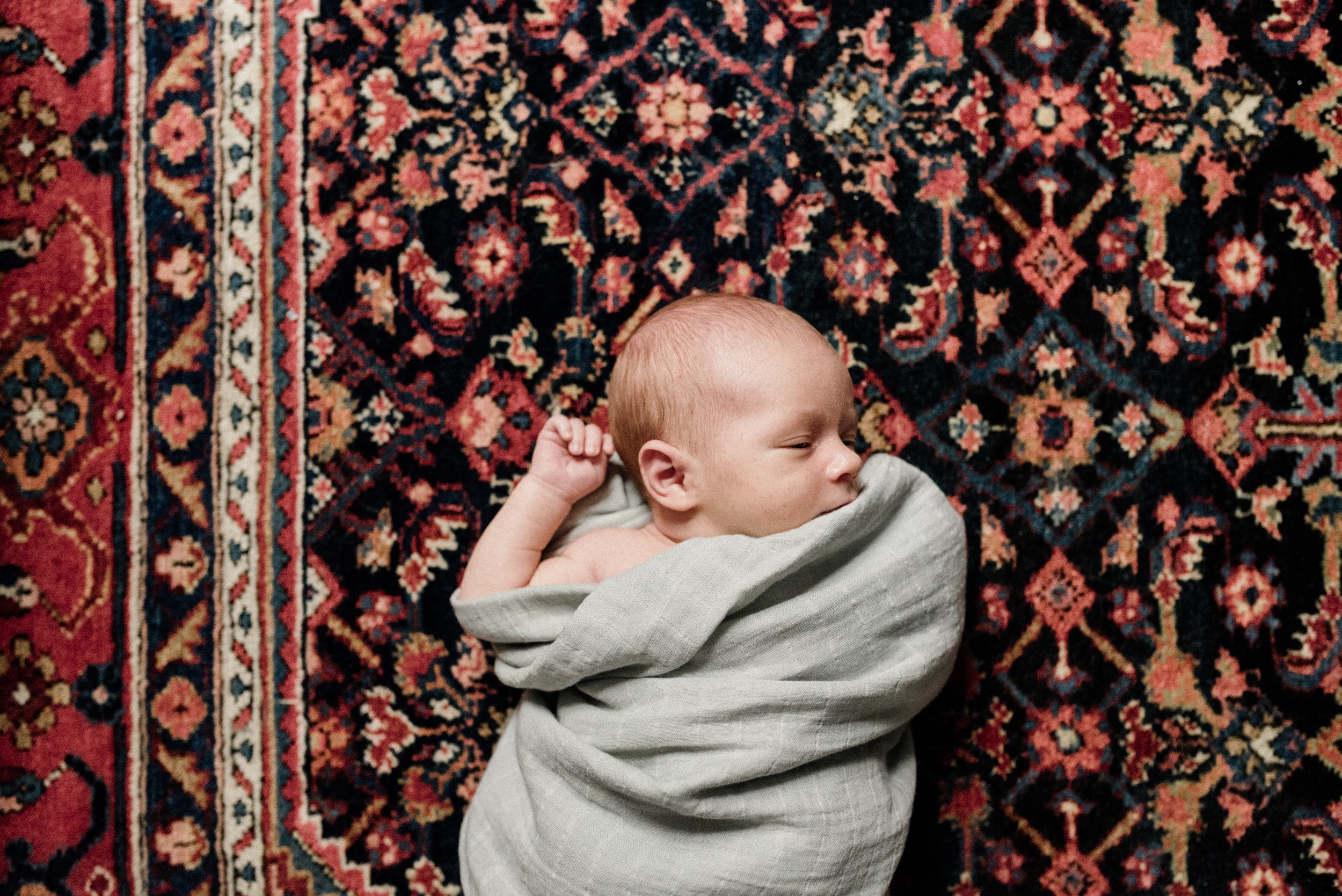 portrait of newborn lying down on persian style carpet