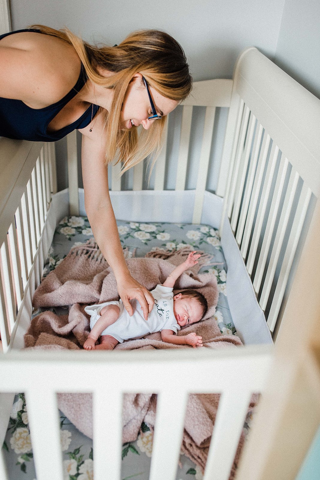 New mom cuddling her new baby in her flower pattern crib