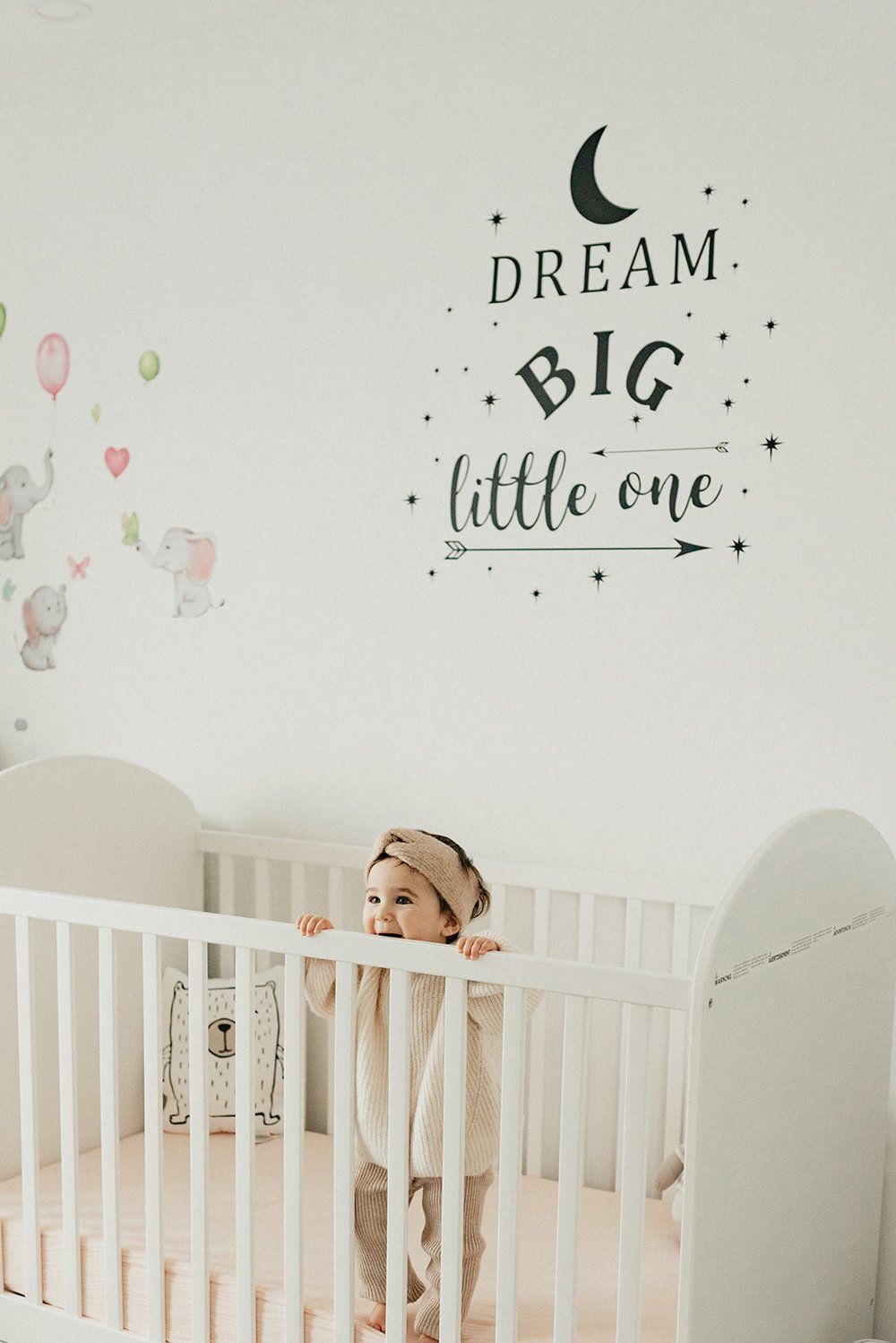 Photo of baby standing in her white crib