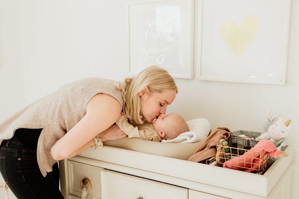 New mom kissing her baby on the changing table