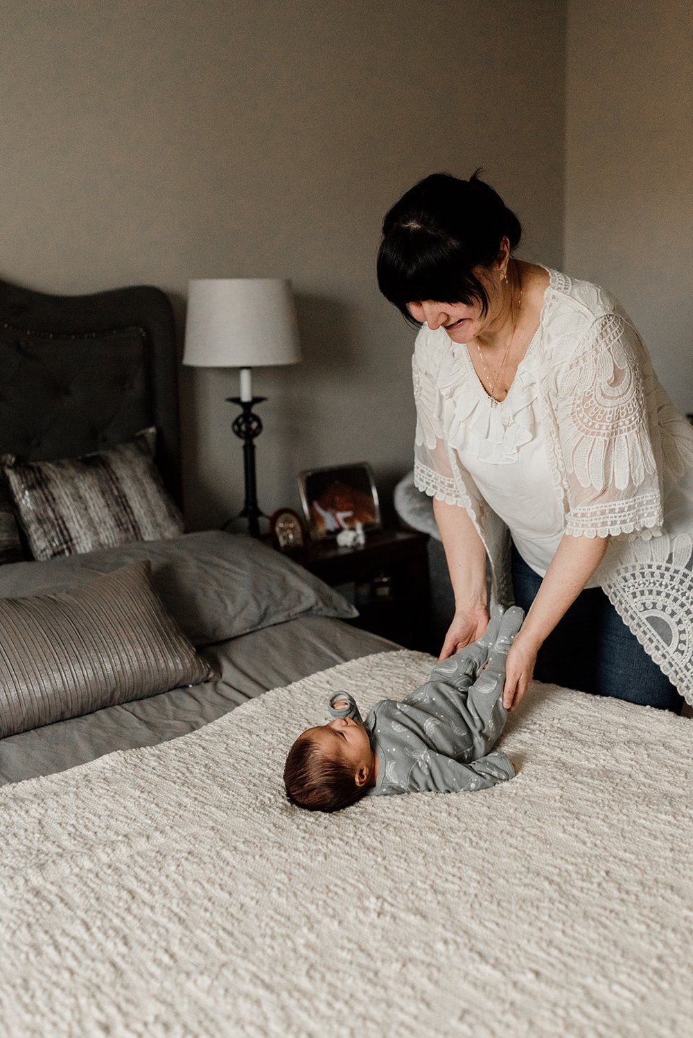 picture of a beautiful mom changing her baby on the bed at home