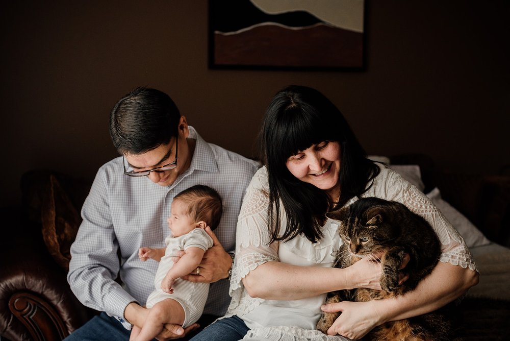 new parents cuddling with their newborn and cat at home, whitby