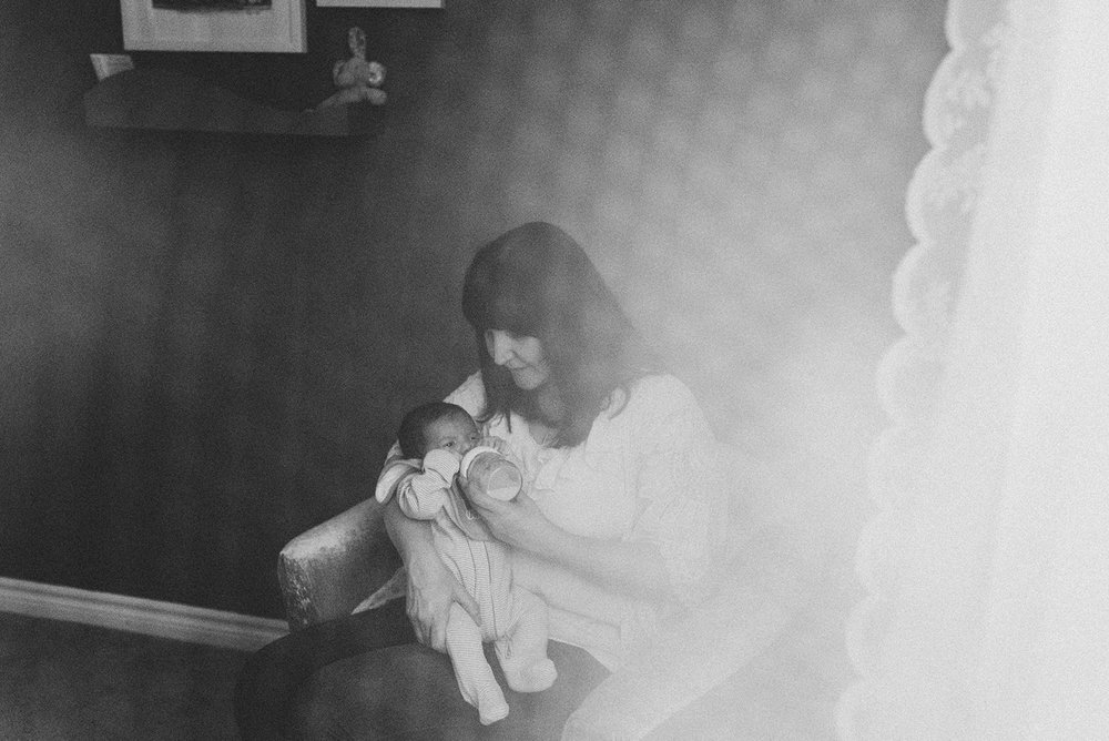dreamy image of mom feeding her newborn with a bottle at home in Whitby