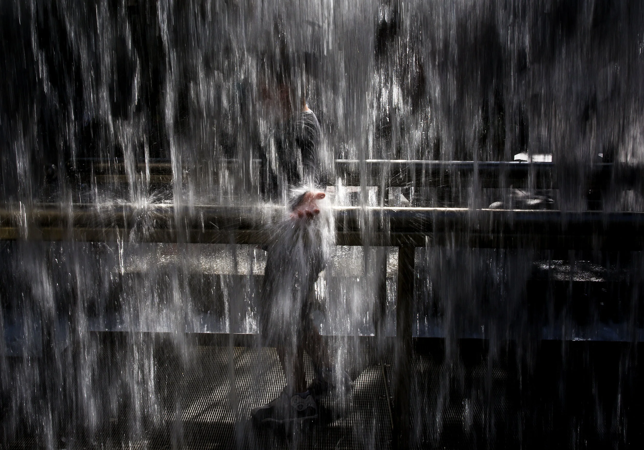 A child reaches his hand into the fountain at Westlake Park in downtown Seattle to cool down in the summer heat, Friday, June 2, 2017. (Sy Bean / Seattle Refined)