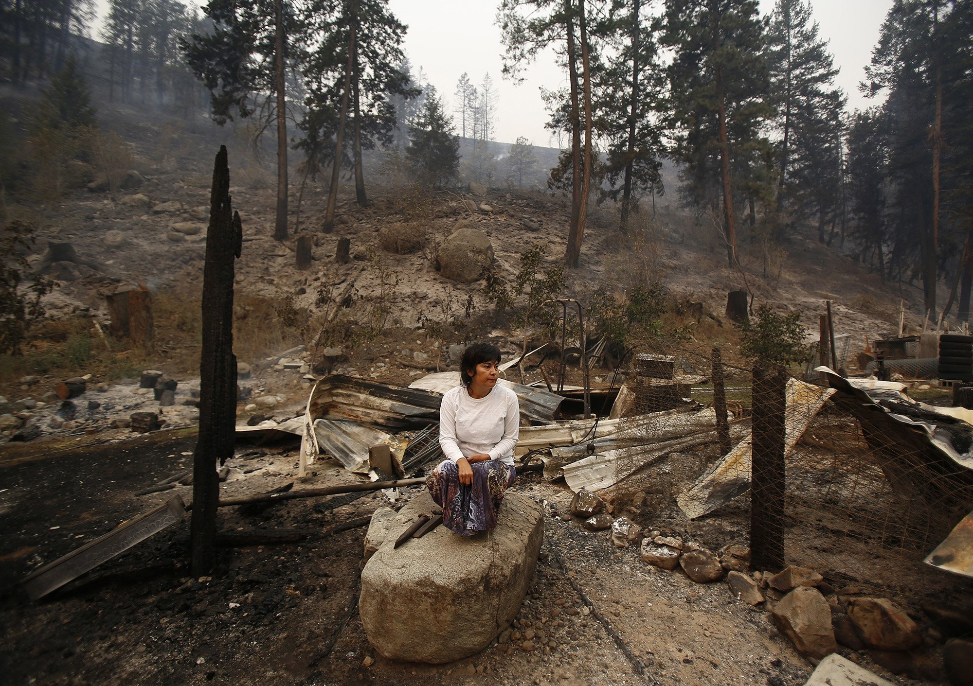  Sandra Gomez sits on amongst the rubble of her home of 30 years that was taken by the fire storm that swept through Antoine Creek the night before, on Saturday, Aug. 15, 2015. 