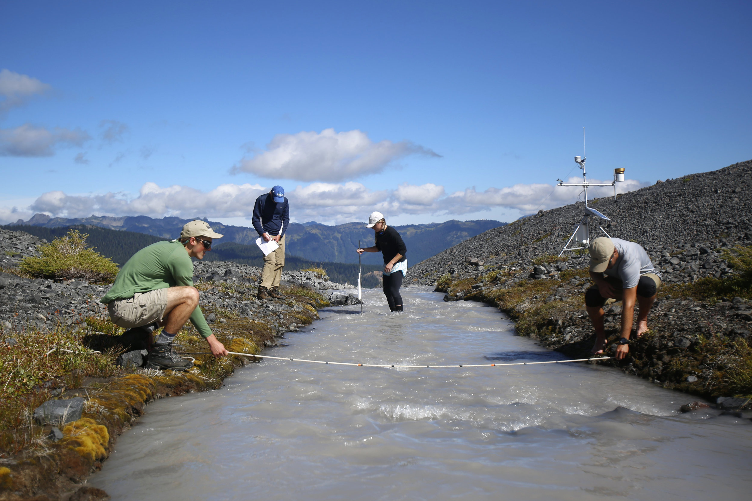  Erica Nied, center, makes her way across the icy runoff stream of Sholes Glacier to take depth measurements as Mauri Pelto records the data. Tyler Sullivan, right, and Ben Pelto, left, measure the width of the stream.     