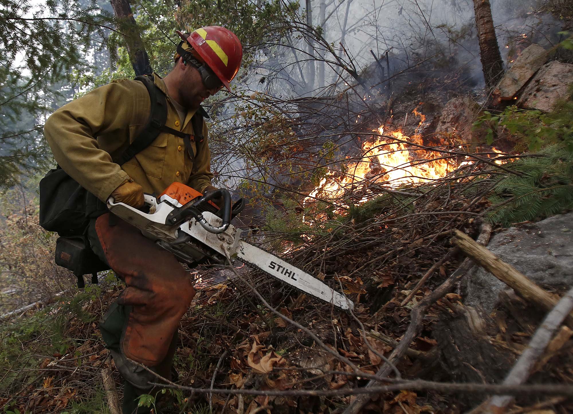  Adam Jordan from Oregon heads back uphill after clearing brush at the First Creek Fire in the Lake Chelan State Park on Sunday, Aug. 16, 2015. 