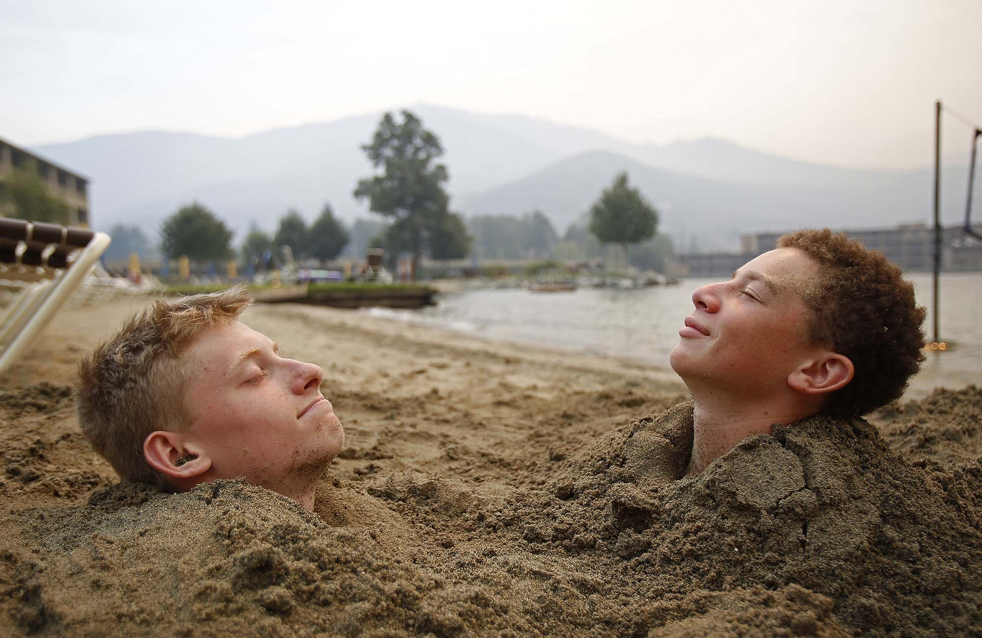  (Left to right) Harrison Noble, 16, and Max Jinjika, 14, relax in the sun on the beach outside of Campbell's Resort at Lake Chelan on Sunday, Aug. 16, 2015. 