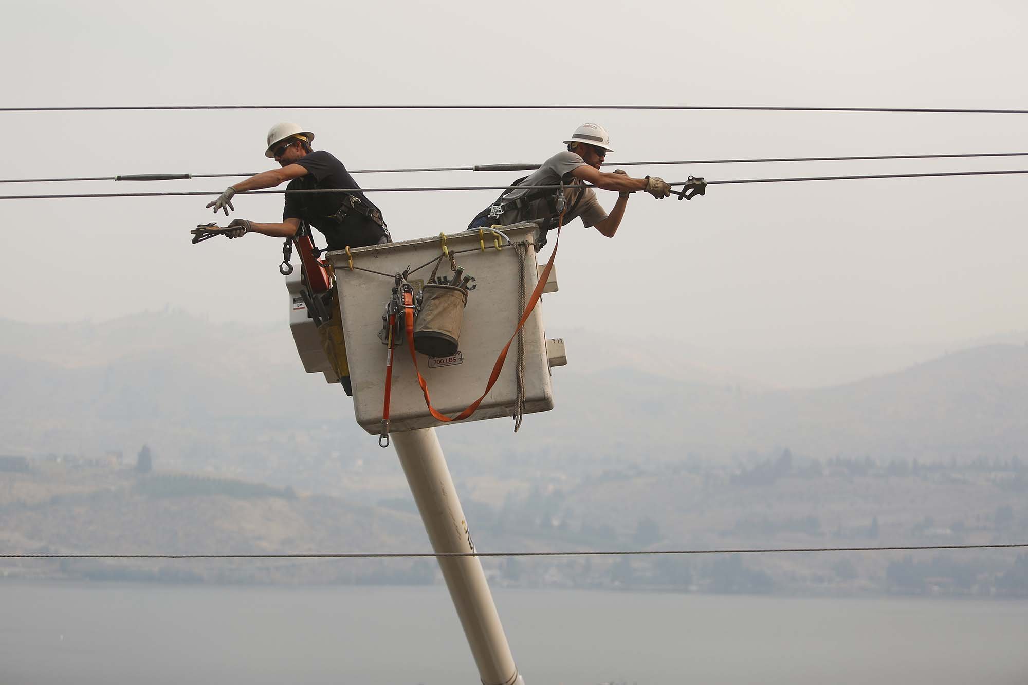  Chelan County PUD linesman Jared Montgomery, left, and Joel Macintosh, right, work on restoring power to the city of Chelan early on Sunday morning as smoke fills the lake, Aug. 16, 2015. Some 9,000 homes were without power last night, and linesman 