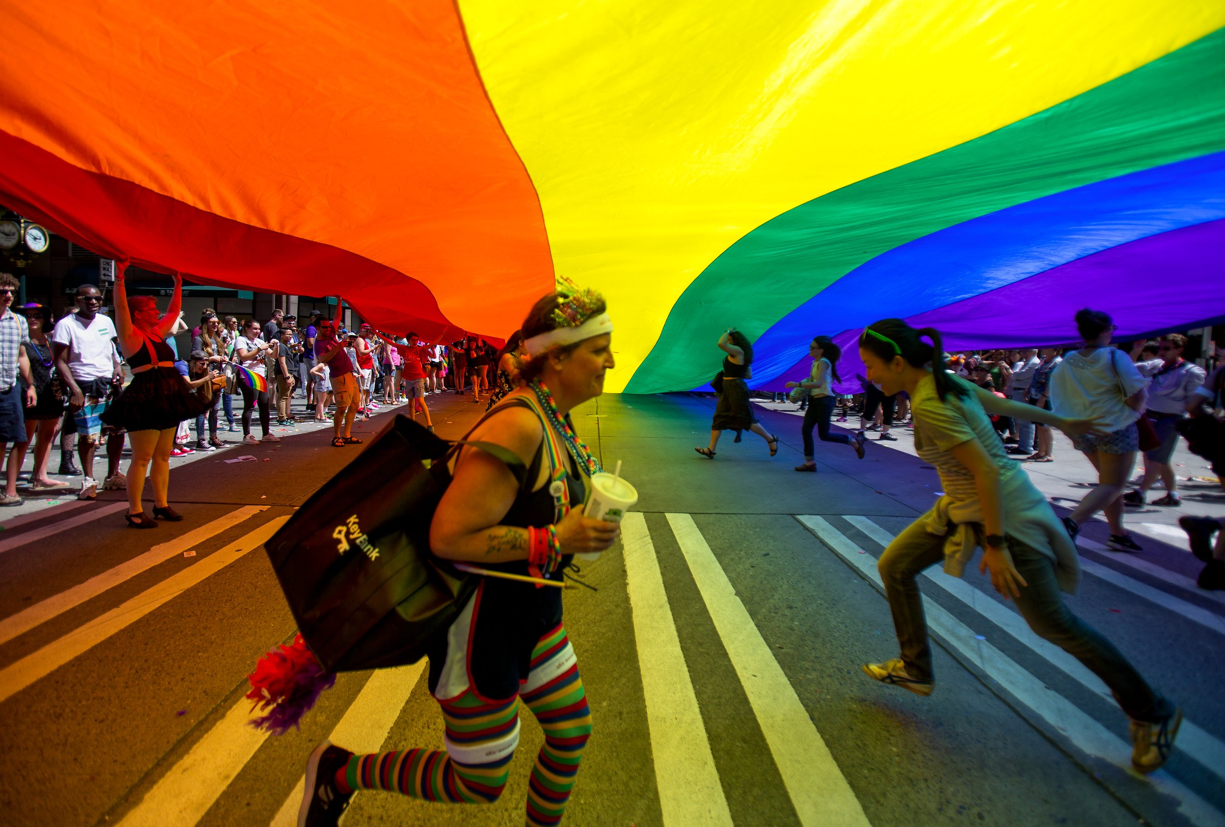  Spectators run underneath the largest Pride flag in the city of Seattle during the annual Pride parade, Sunday, June 26, 2016. (Sy Bean / Seattle Times) 