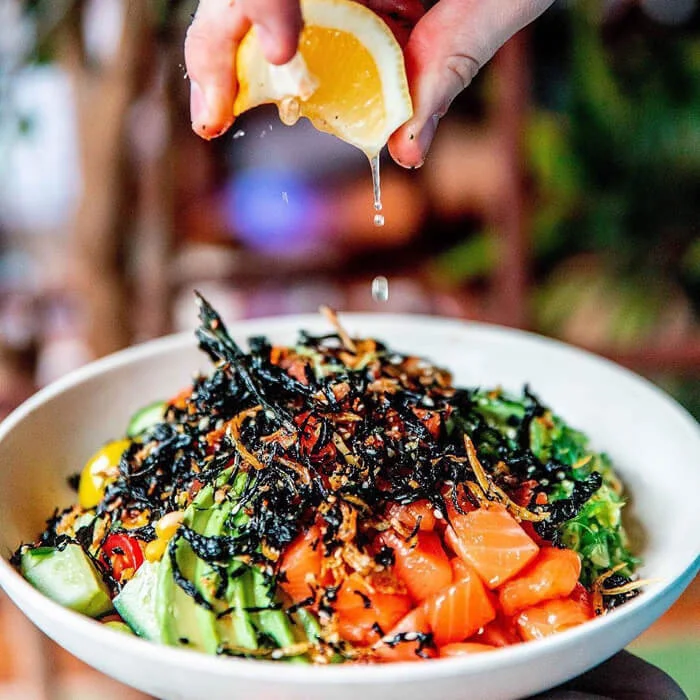 Photo of one of our restaurant marketing team squeezing lemon on poke for Salmon &amp; B ear