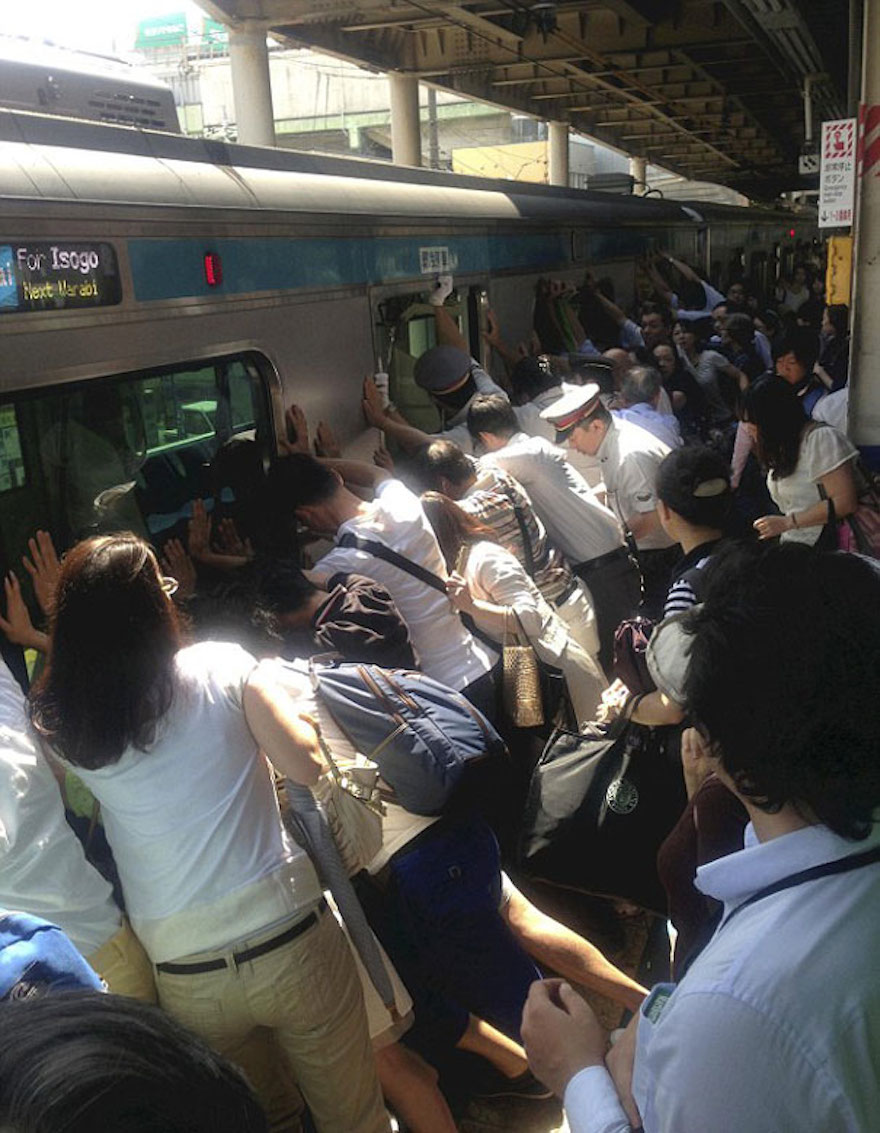 A mass of Japanese train passengers work together to push a 32-ton train car away from the platform in order to free a woman trapped in a gap.