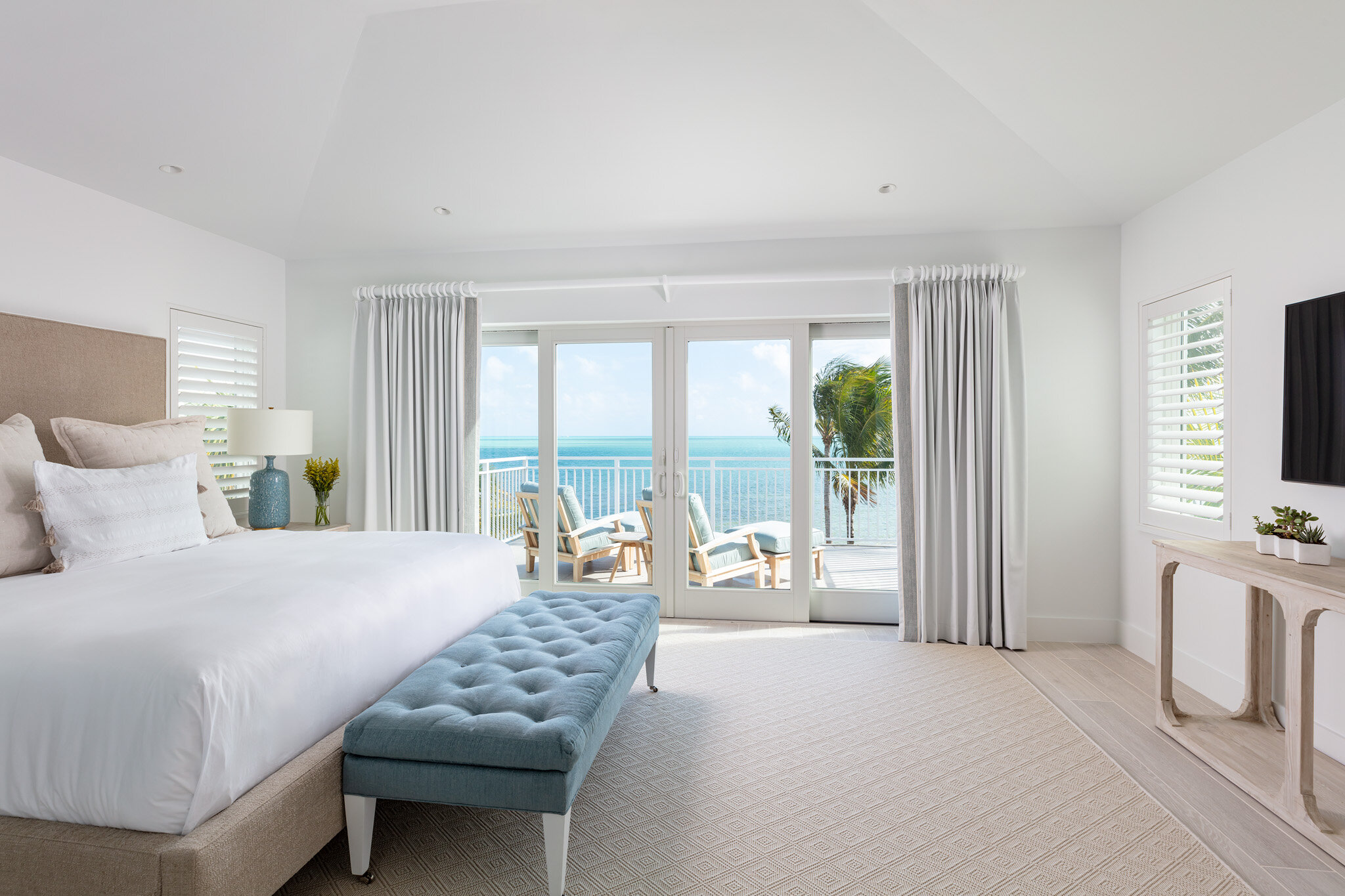  Master bedroom suite with large king bed and sliding door access to balcony with ocean view on the second floor of an Islands waterfront villa. 