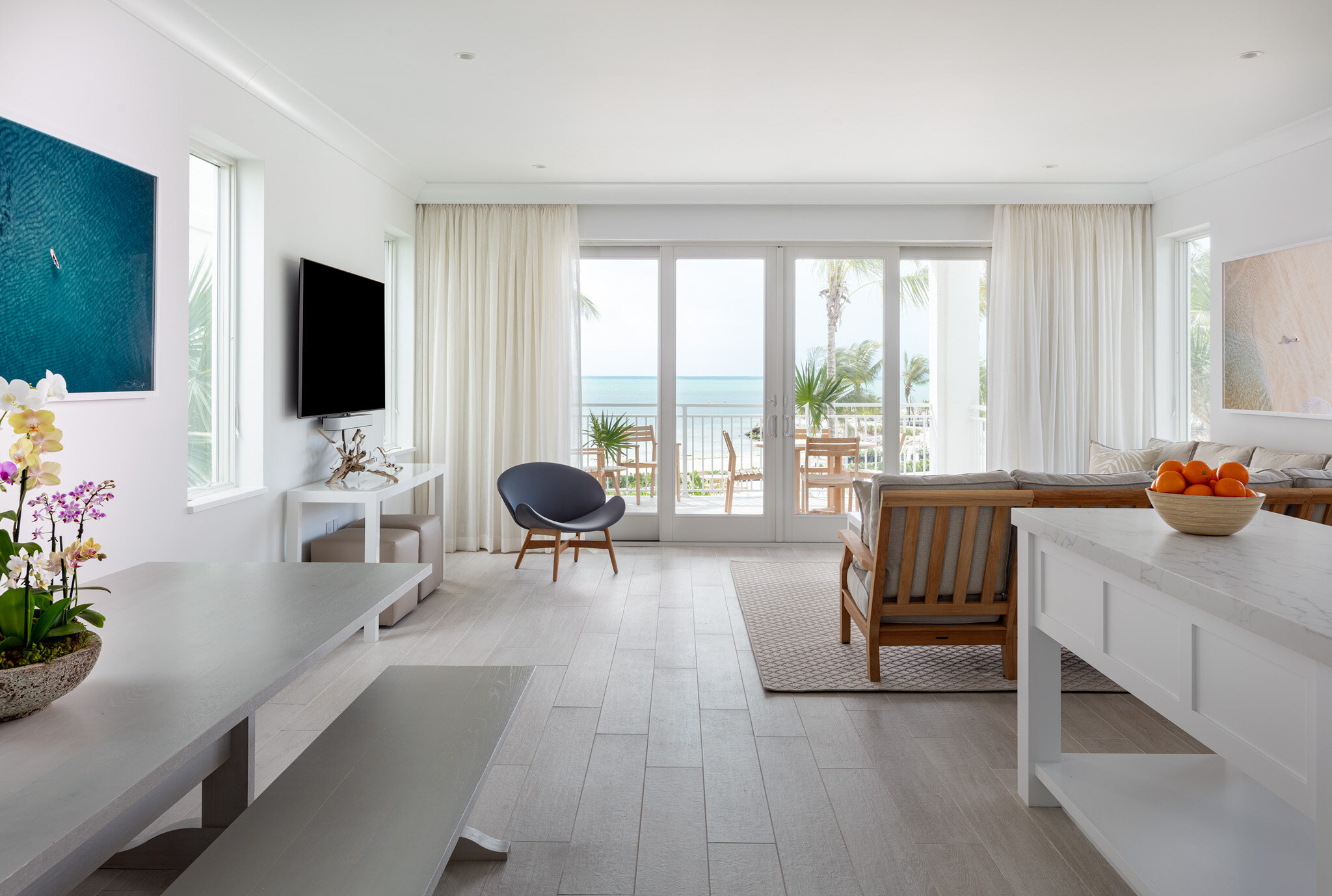  Living room, dining area, and kitchen in an Islands waterfront villa with sliding glass door to balcony with a view of the Atlantic Ocean. 