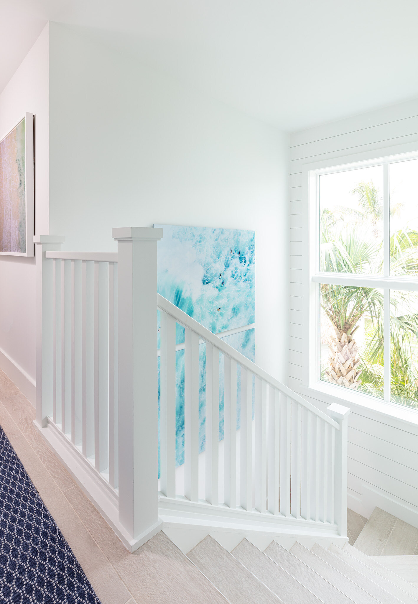  Stairwall with wall art and large window in an Islands waterfront villa. 