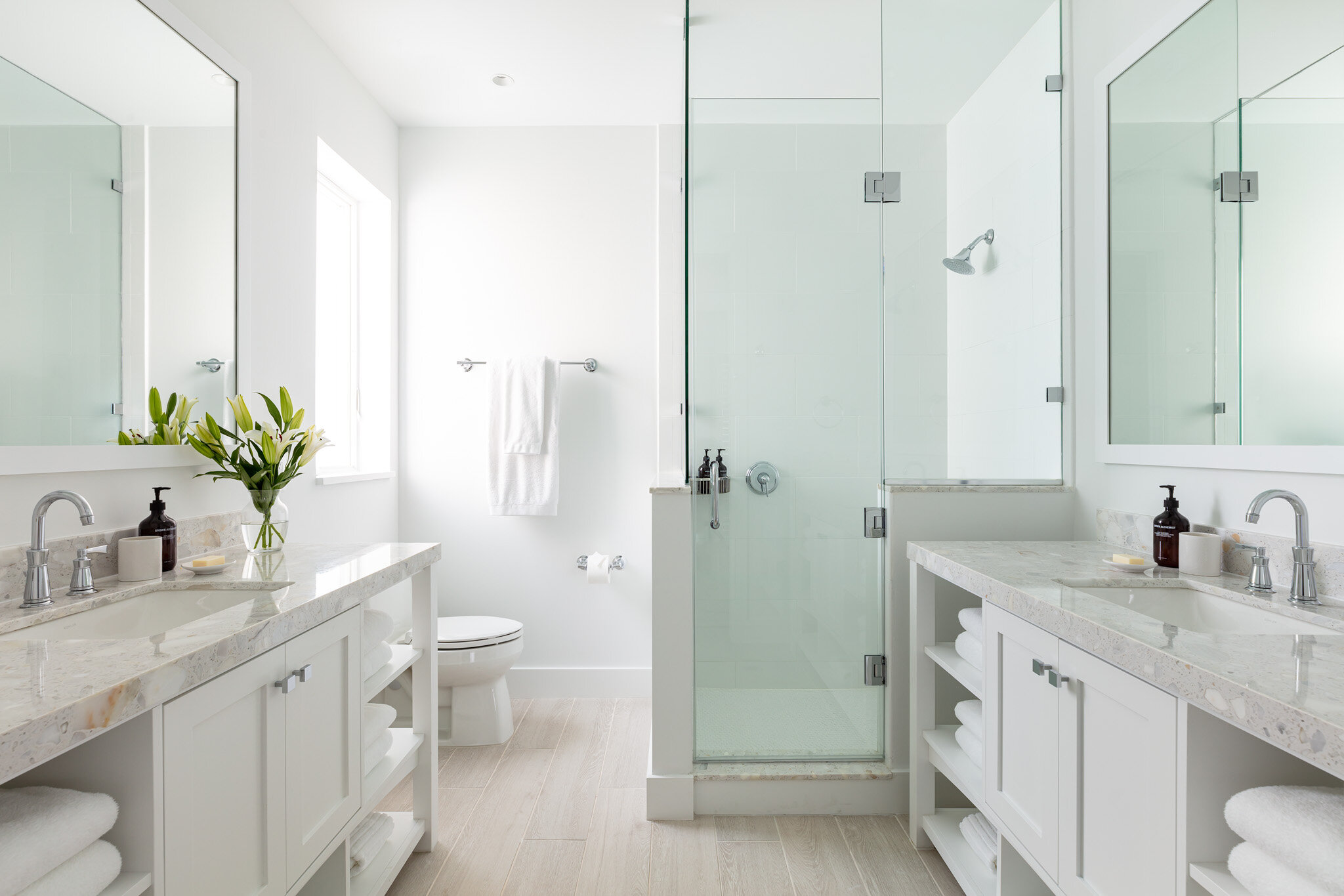  Bathroom with two sinks and mirrors on opposite facing walls, shower stall, and toilet in an Islands waterfront villa. 