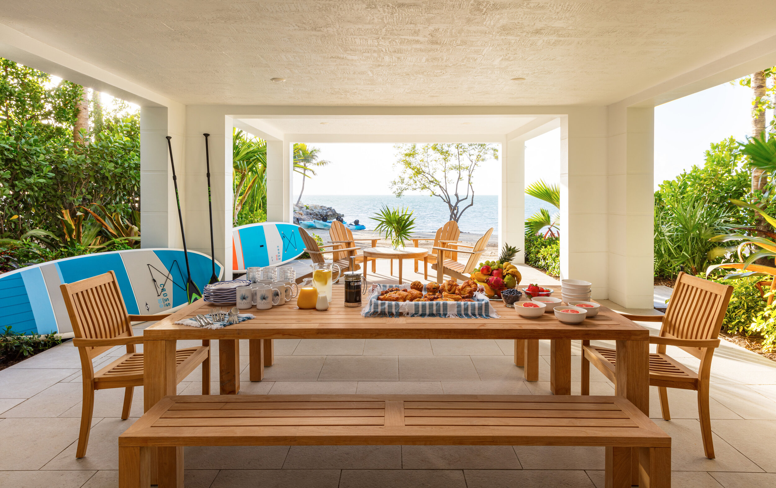  Table set for a meal on the covered patio of an Islands waterfront villa with an ocean view. 