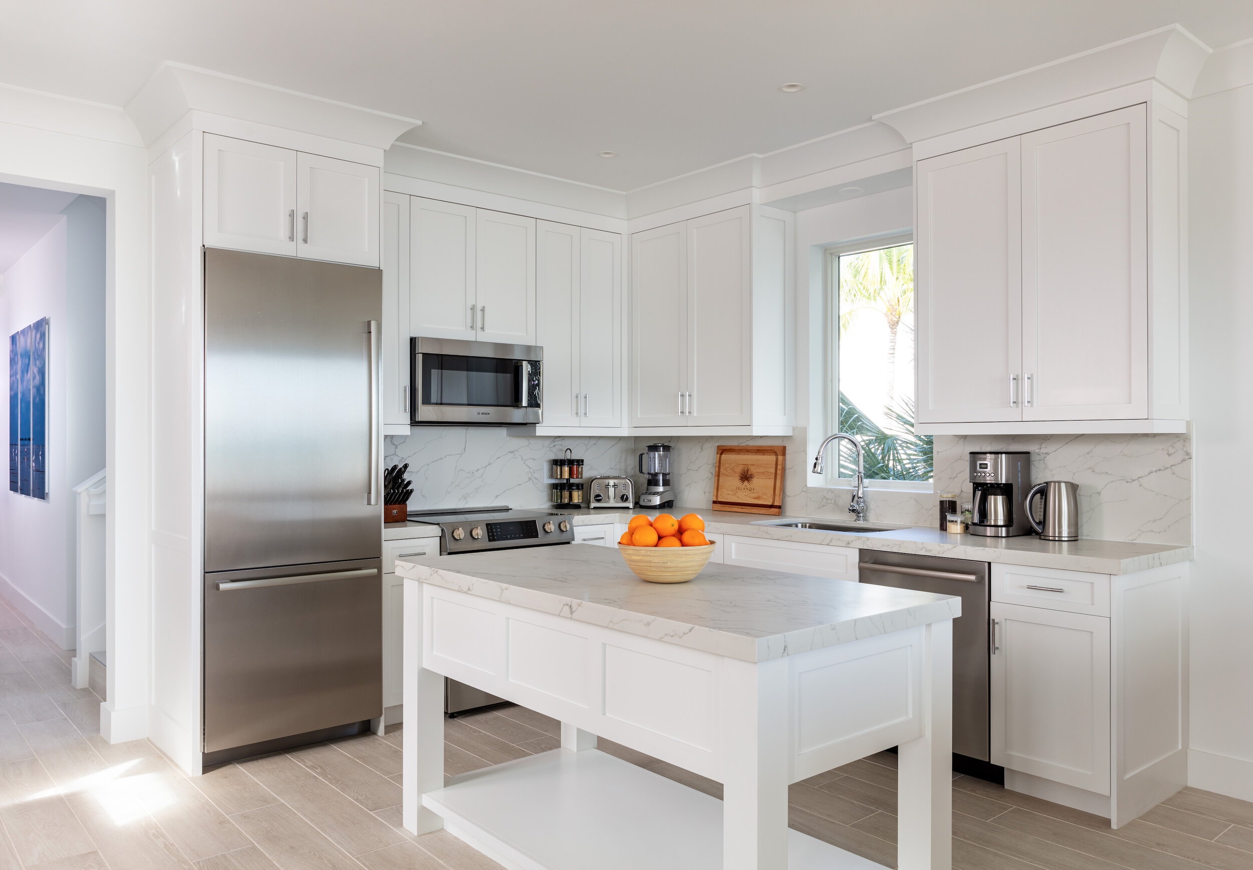  Furnished kitchen in an Islands waterfront villa with island table, refrigerator, microwave, stove, and other kitchen essentials. 