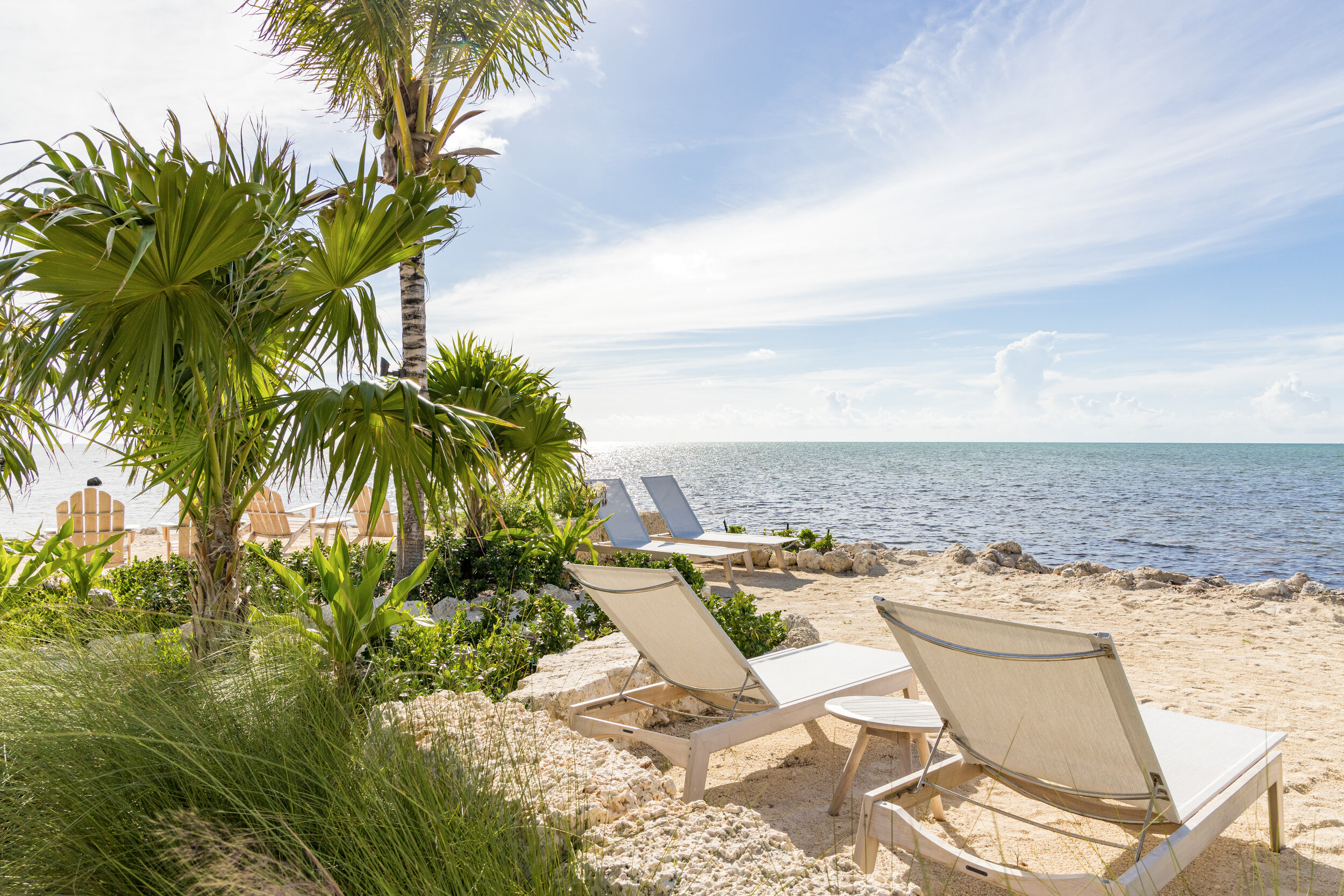  Lounge chairs and palm trees on The Islands of Islamorada’s private beach looking out onto the crystal clear waters of the Atlantic Ocean. 