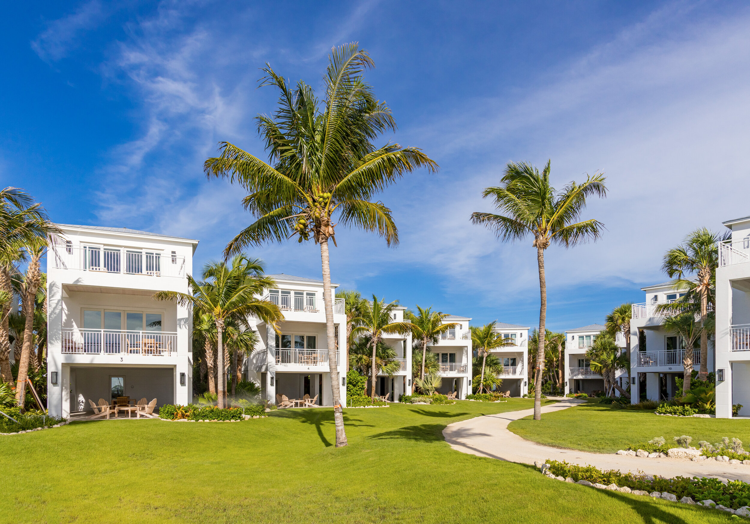  View of The Islands of Islamorada’s ocean view villas and open lawn lined with palm trees. 