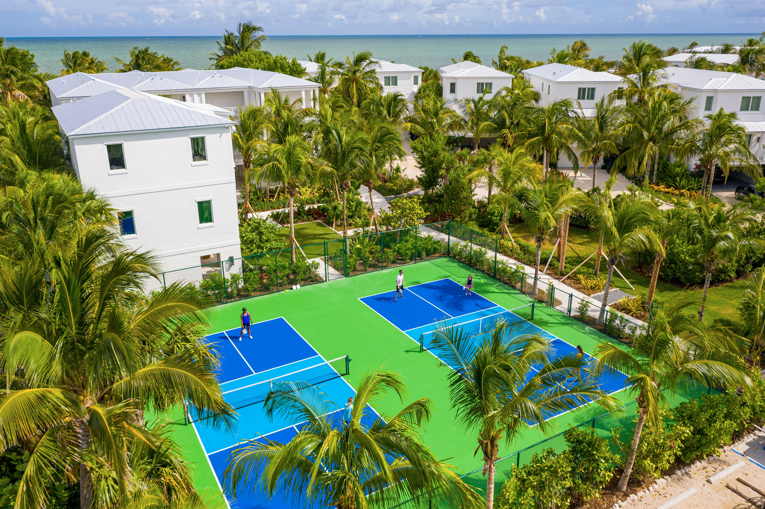  Aerial view of The Islands of Islamorada’s pickleball courts surrounded by palm trees and a view of the Atlantic Ocean. 