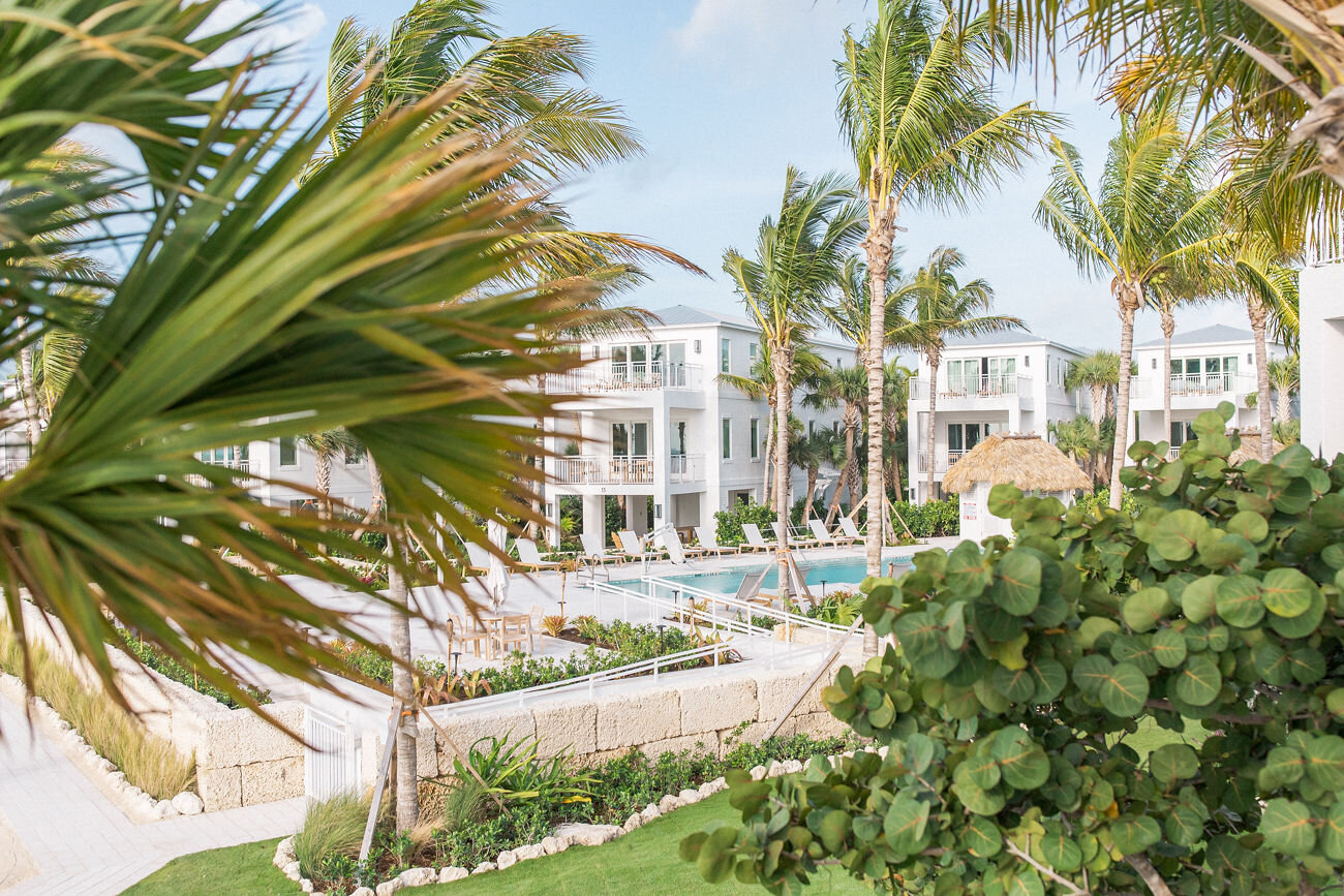  Partial view of The Islands of Islamorada’s villas and private pool through a clearing of palm trees. 